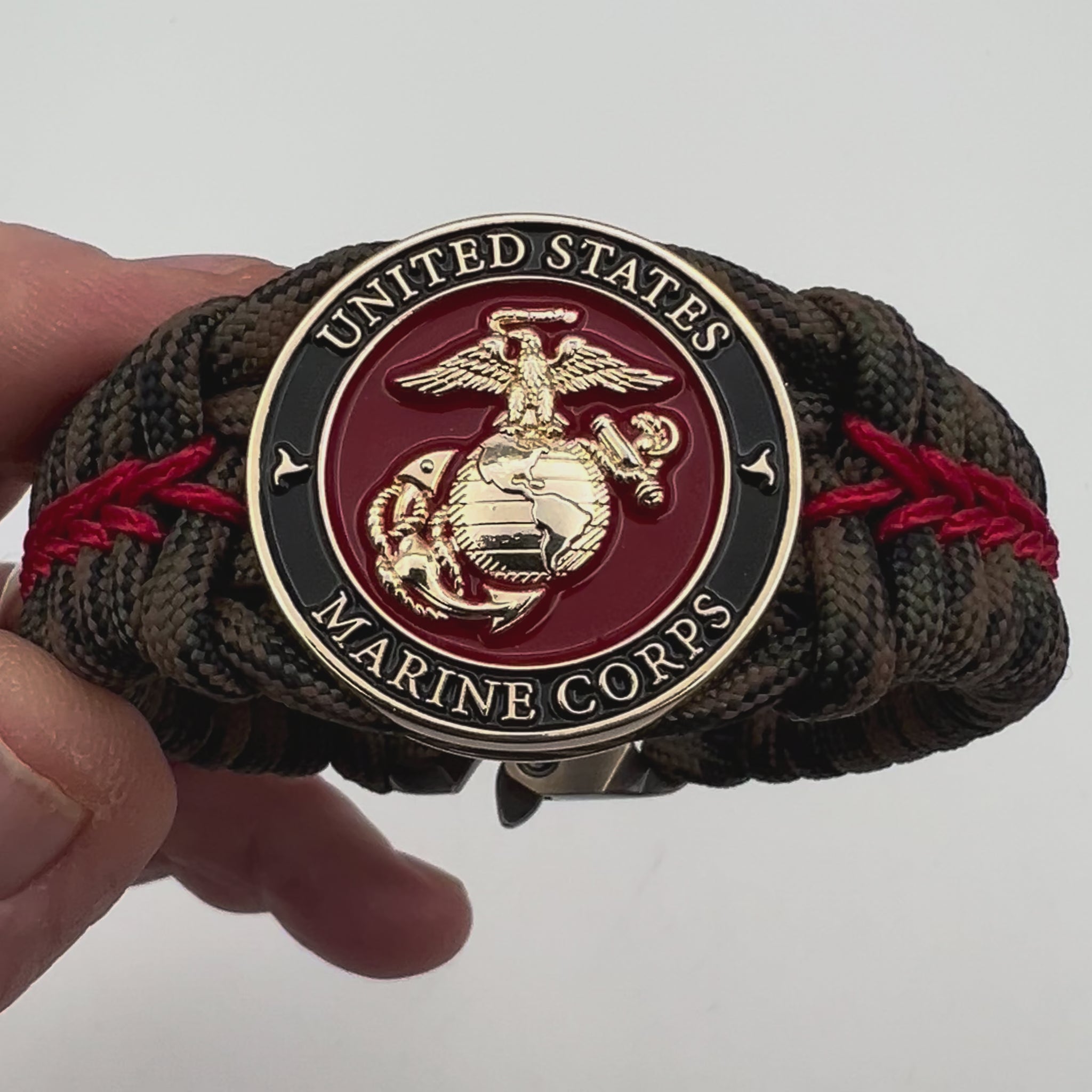 Thick, rigid and comfortable braided United States Marine Corps bracelet featuring a 24K gold plated USMC Eagle Globe and Anchor medallion, a gold Cobra style tactical buckle and woven with Woodland Camo 550 paracord and Imperial Red micro cord.