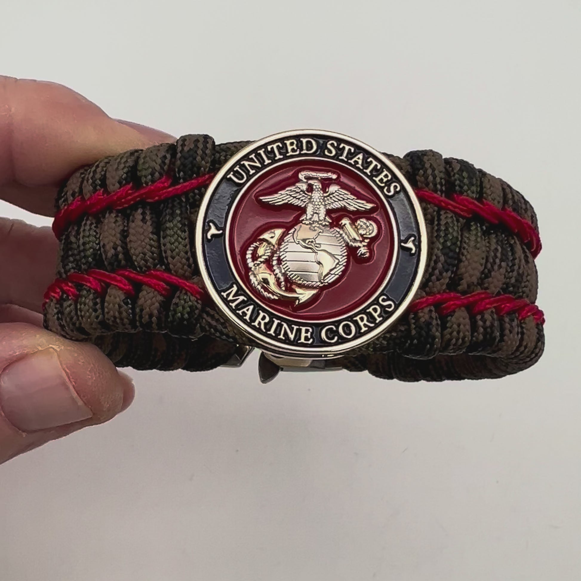 Thick, rigid and comfortable braided United States Marine Corps bracelet featuring a 24K gold and silver plated USMC officer Eagle Globe and Anchor medallion, a gold Cobra style tactical buckle and woven with Woodland Camo 550 paracord and Imperial Red micro cord.