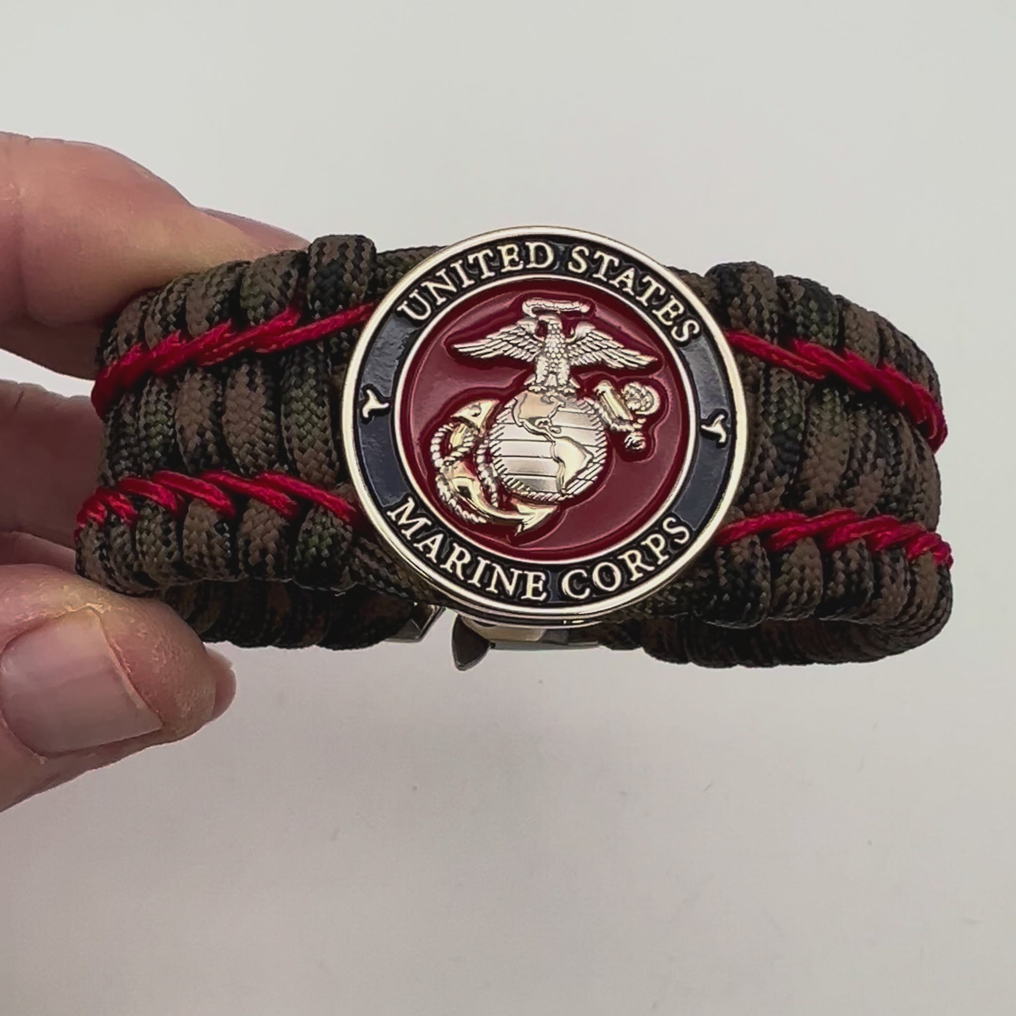 Thick, rigid and comfortable braided United States Marine Corps bracelet featuring a 24K gold and silver plated USMC officer Eagle Globe and Anchor medallion, a gold Cobra style tactical buckle and woven with Woodland Camo 550 paracord and Imperial Red micro cord.