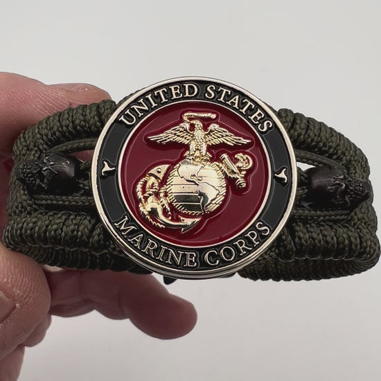 Thin, medium width, flexible and comfortable braided United States Marine Corps bracelet featuring a 24K gold plated USMC officer Eagle Globe and Anchor medallion, two black micro skulls, a black Cobra style tactical buckle and woven with Olive Drab Type-1 paracord.