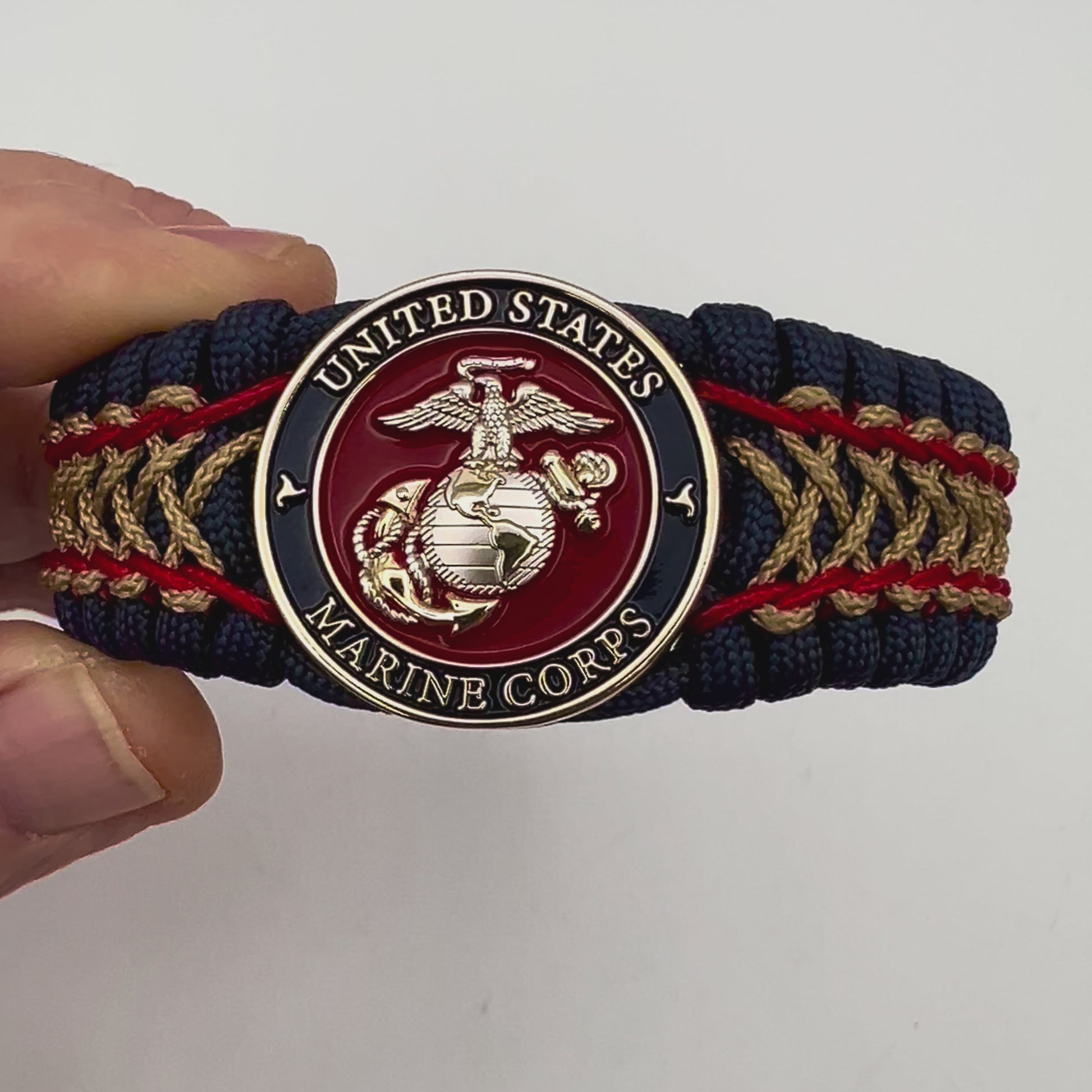 Thick and comfortable braided United States Marine Corps bracelet featuring a 24K gold and silver plated USMC officer Eagle Globe and Anchor medallion, a Cobra style tactical buckle and woven with gold 550 paracord and Imperial Red and Gold micro cord.