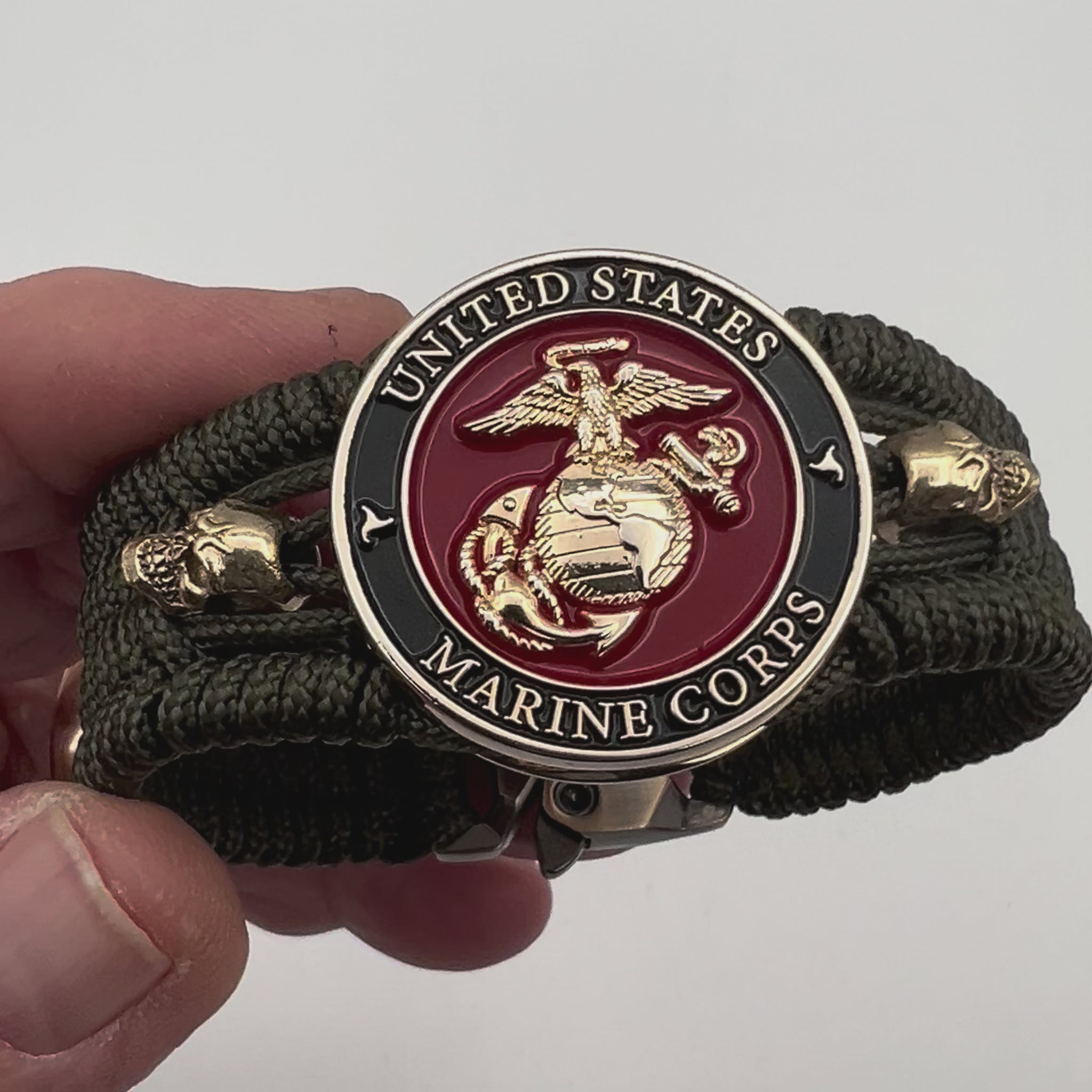 Thin, medium width, flexible and comfortable braided United States Marine Corps bracelet featuring a 24K gold plated USMC officer Eagle Globe and Anchor medallion, two gold plated skulls, a gold Cobra style tactical buckle and woven with Olive Drab Type-1 paracord.