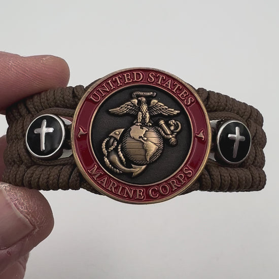 Thin, medium width, flexible and comfortable braided United States Marine Corps bracelet featuring a 24K antique gold plated USMC officer Eagle Globe and Anchor medallion, two Christian crosses, a black Cobra style tactical buckle and woven with Coyote Brown Type-1 paracord.