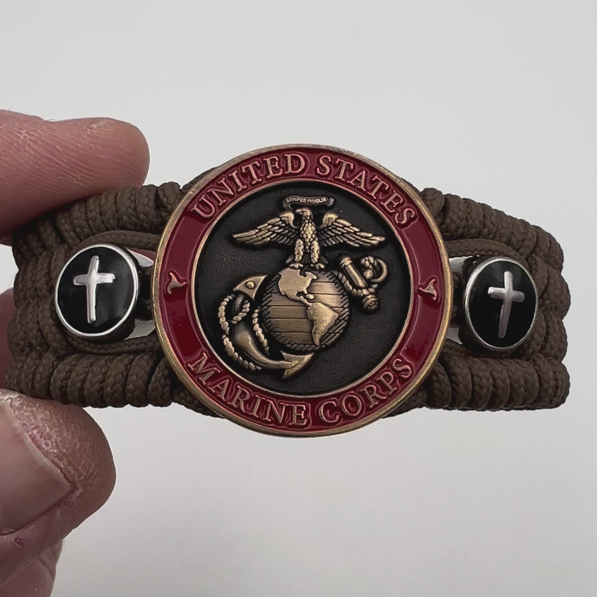 Thin, medium width, flexible and comfortable braided United States Marine Corps bracelet featuring a 24K antique gold plated USMC officer Eagle Globe and Anchor medallion, two Christian crosses, a black Cobra style tactical buckle and woven with Coyote Brown Type-1 paracord.