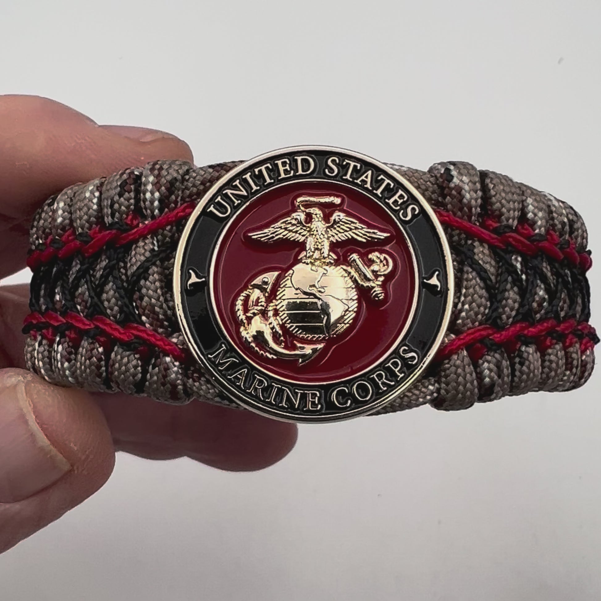 Thick, wide, rigid and comfortable braided United States Marine Corps bracelet featuring a 24K gold plated USMC Eagle Globe and Anchor medallion, a gold Cobra style tactical buckle and woven with Desert Camo 550 paracord, Imperial Red micro cord and black nano cord.