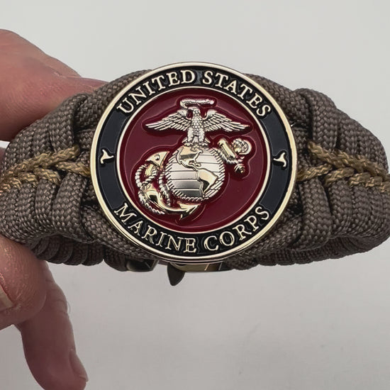 Thick, semi-rigid and comfortable braided United States Marine Corps bracelet featuring a 24K gold and silver plated USMC officer Eagle Globe and Anchor medallion, a gold Cobra style tactical buckle and woven with tan 550 paracord and gold micro cord.