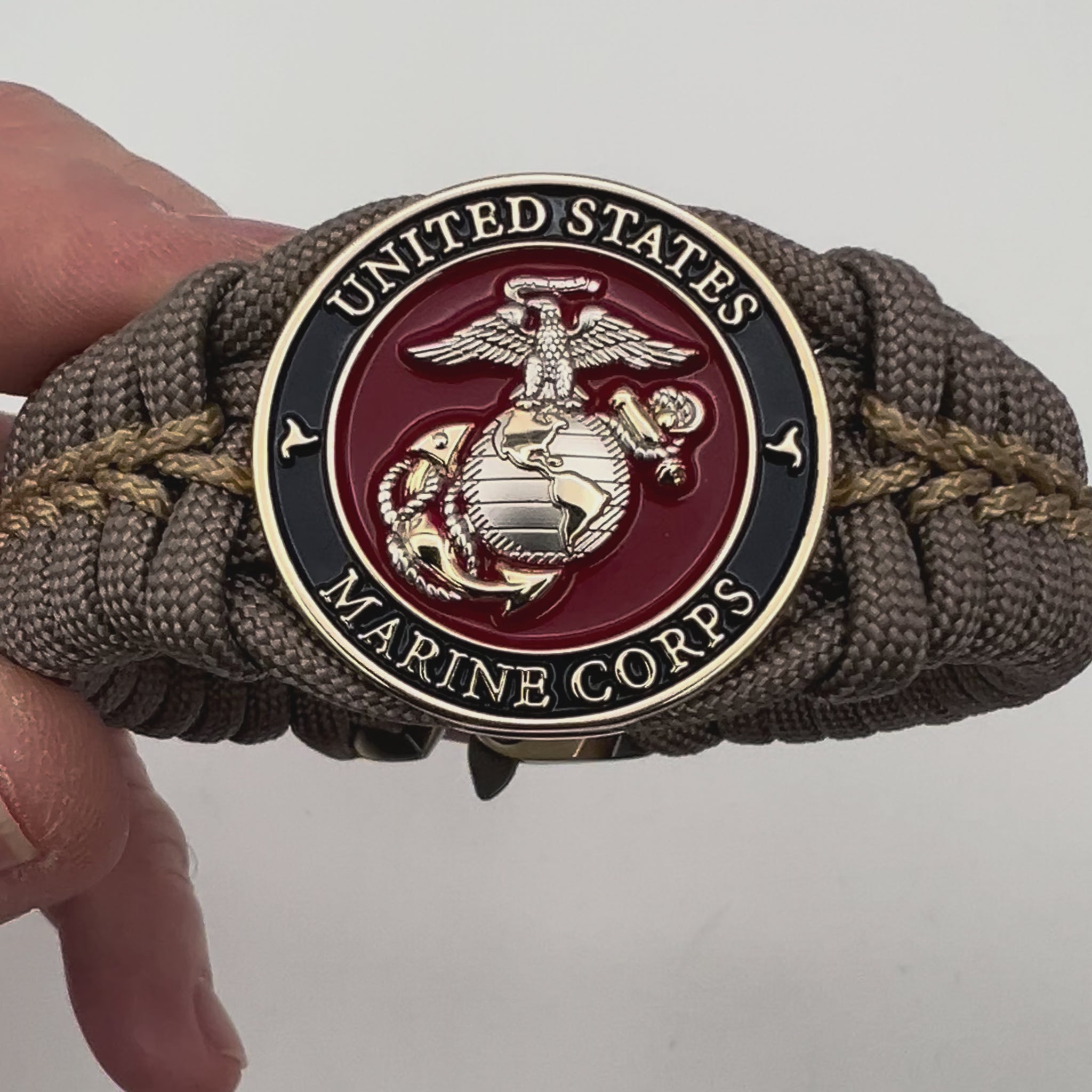Thick, semi-rigid and comfortable braided United States Marine Corps bracelet featuring a 24K gold and silver plated USMC officer Eagle Globe and Anchor medallion, a gold Cobra style tactical buckle and woven with tan 550 paracord and gold micro cord.