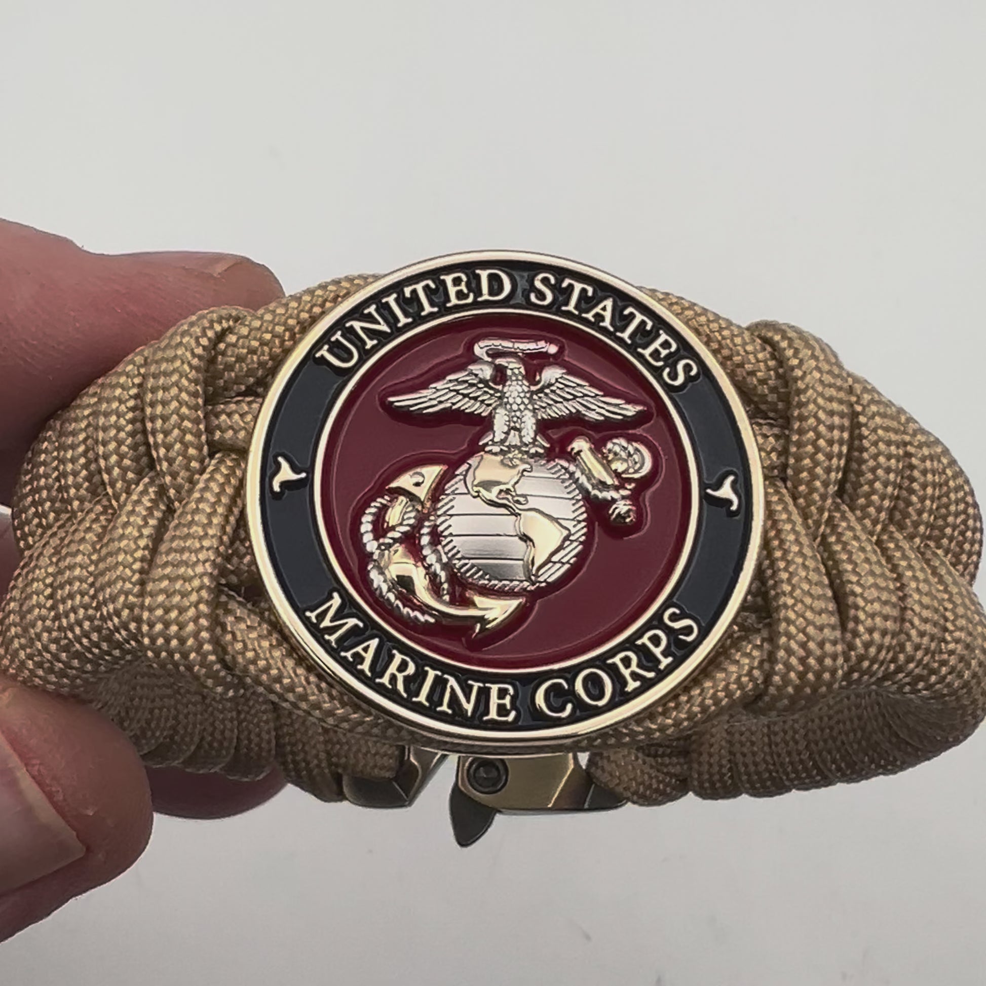 Thick and comfortable braided United States Marine Corps bracelet featuring a 24K gold and silver plated USMC officer Eagle Globe and Anchor medallion, a Cobra style tactical buckle and woven with gold 550 paracord.