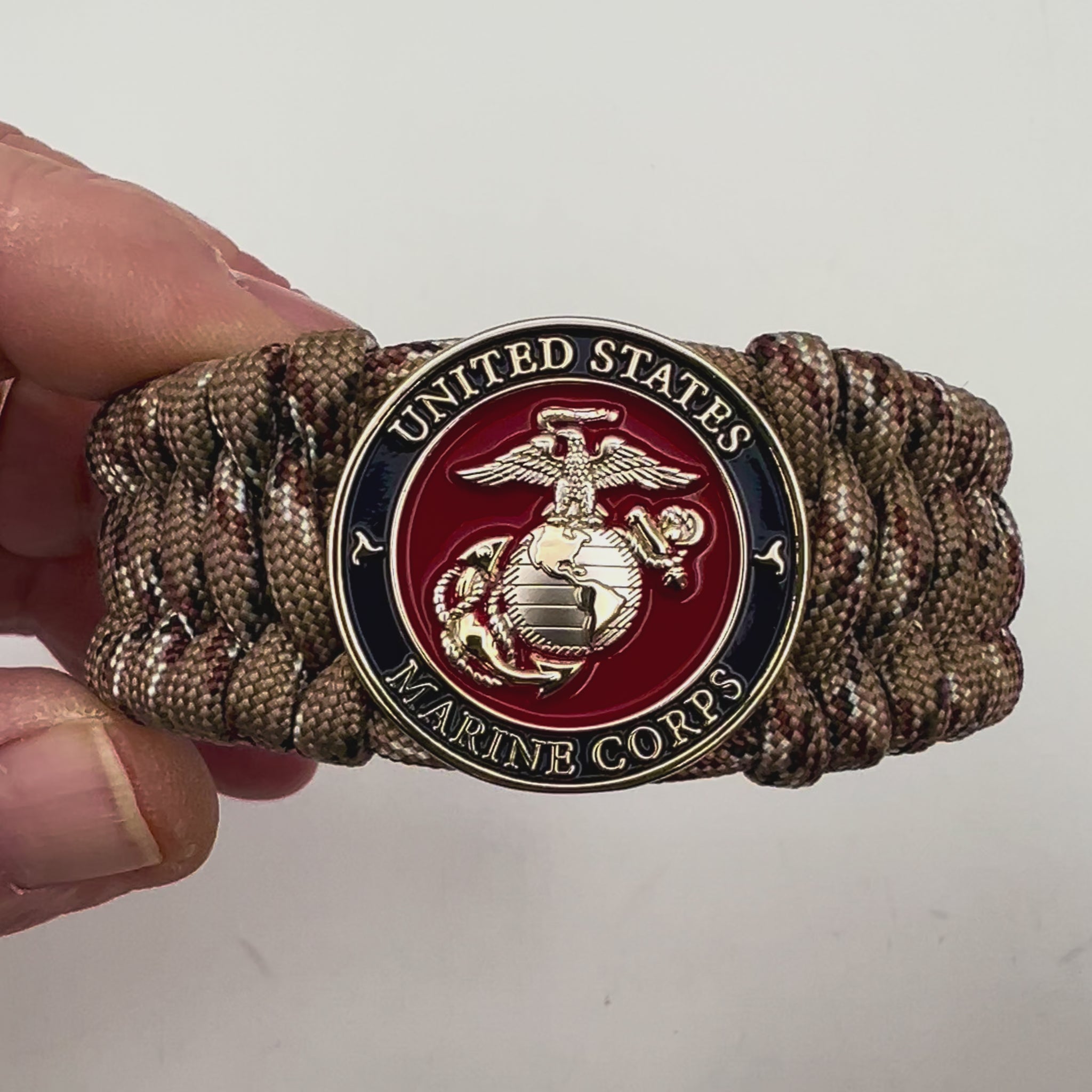 Thick and comfortable braided United States Marine Corps bracelet featuring a 24K gold and silver plated USMC officer Eagle Globe and Anchor medallion, a gold Cobra style tactical buckle and woven with Desert Camo 550 paracord.