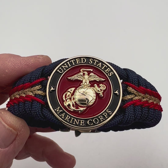 Thick, rigid and comfortable braided United States Marine Corps bracelet featuring a 24K gold plated USMC Eagle Globe and Anchor medallion, a gold Cobra style tactical buckle and woven with Navy Blue 550 paracord and Imperial Red and Gold micro cord.