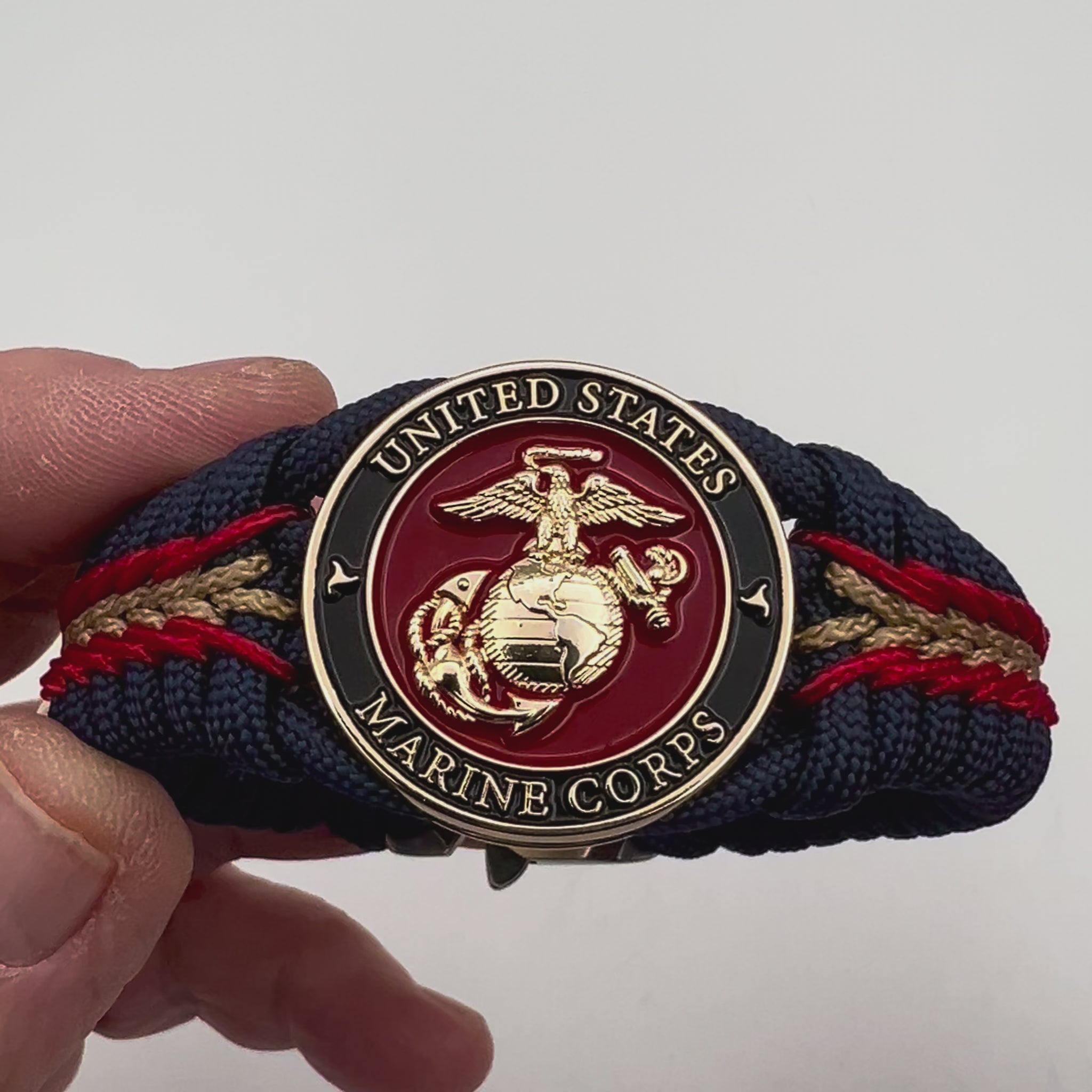 Thick, rigid and comfortable braided United States Marine Corps bracelet featuring a 24K gold plated USMC Eagle Globe and Anchor medallion, a gold Cobra style tactical buckle and woven with Navy Blue 550 paracord and Imperial Red and Gold micro cord.