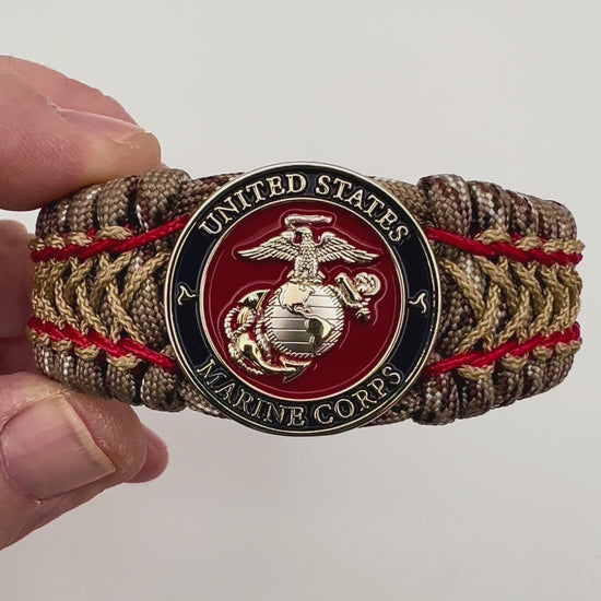Thick and comfortable braided United States Marine Corps bracelet featuring a 24K gold and silver plated USMC officer Eagle Globe and Anchor medallion, a gold Cobra style tactical buckle and woven with Desert Camo 550 paracord and Imperial Red and Gold micro cord.