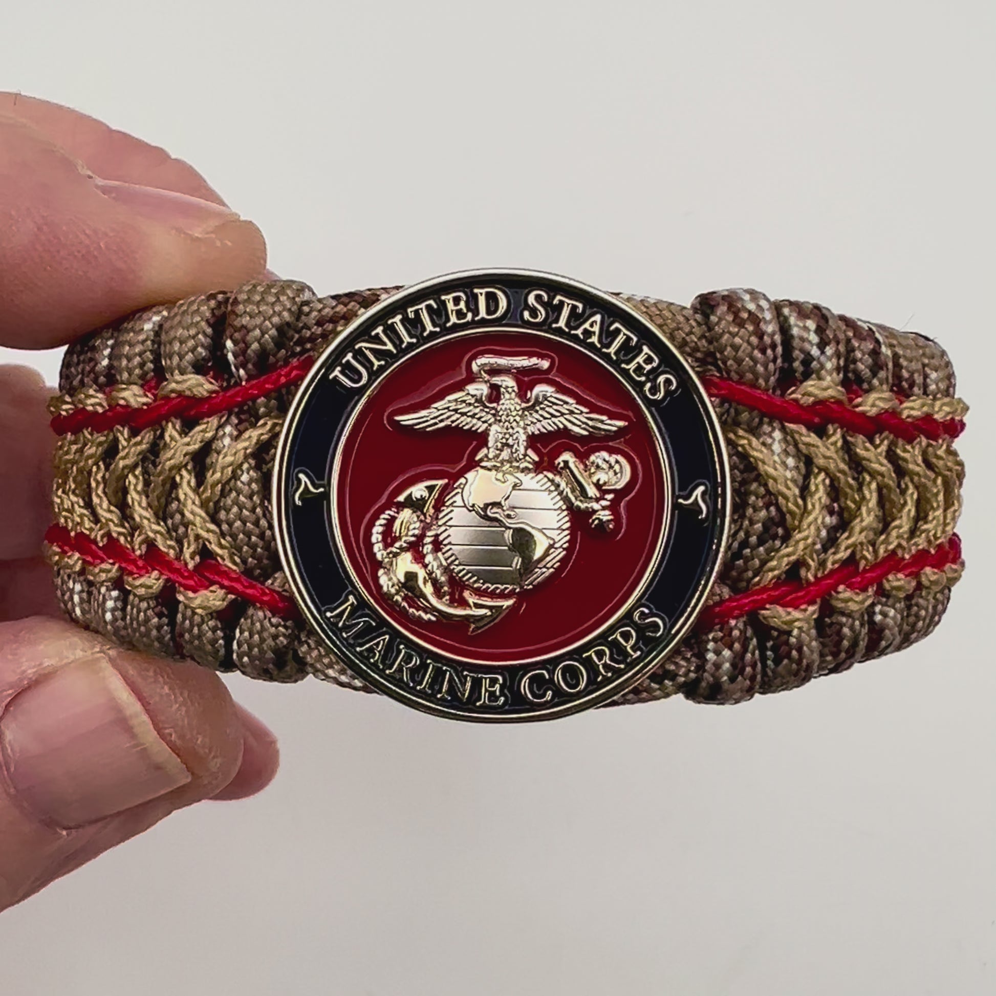 Thick and comfortable braided United States Marine Corps bracelet featuring a 24K gold and silver plated USMC officer Eagle Globe and Anchor medallion, a gold Cobra style tactical buckle and woven with Desert Camo 550 paracord and Imperial Red and Gold micro cord.