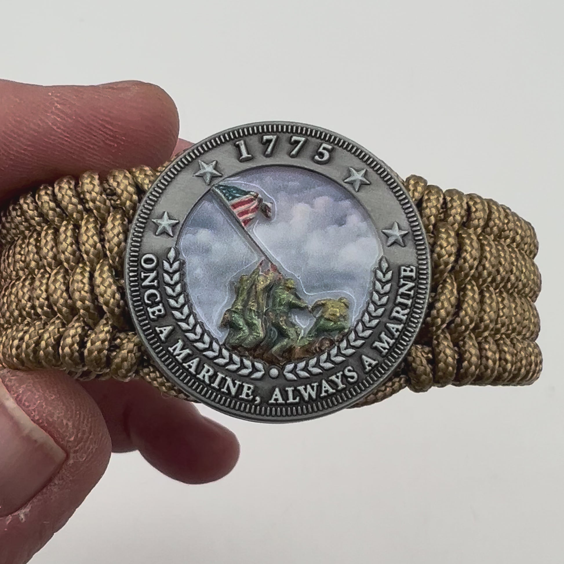 Thin, wide, flexible and comfortable braided United States Marine Corps Iwo Jima bracelet featuring an antique silver plated Iwo Jima flag raising medallion, a gold Cobra style tactical buckle and woven with gold Type-1 paracord.