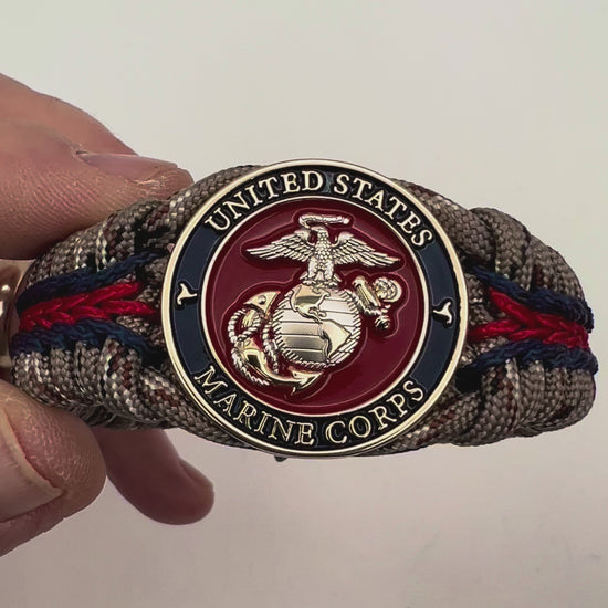 Thick and comfortable braided United States Marine Corps bracelet featuring a 24K gold and silver plated USMC officer Eagle Globe and Anchor medallion, a Cobra style tactical buckle and woven with Desert Camo 550 paracord and Imperial red and Navy Blue micro cord.