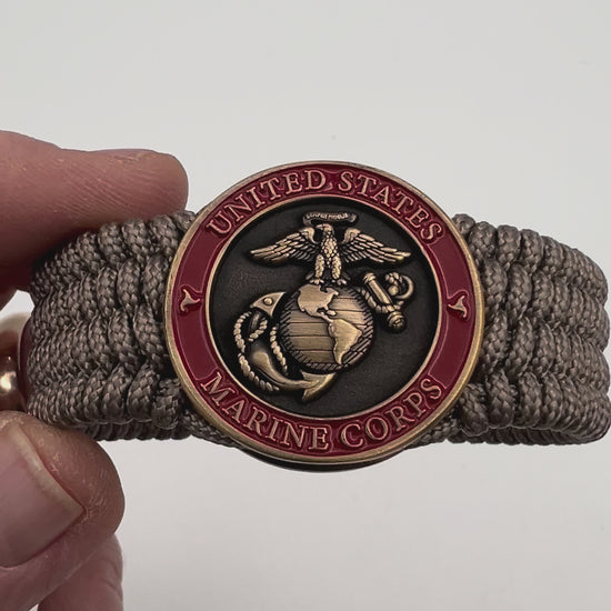 Thin, medium wide, flexible and comfortable braided United States Marine Corps bracelet featuring a 24K antique gold plated USMC Eagle Globe and Anchor medallion, a gold Cobra style tactical buckle and woven with Tan Type-1 paracord.