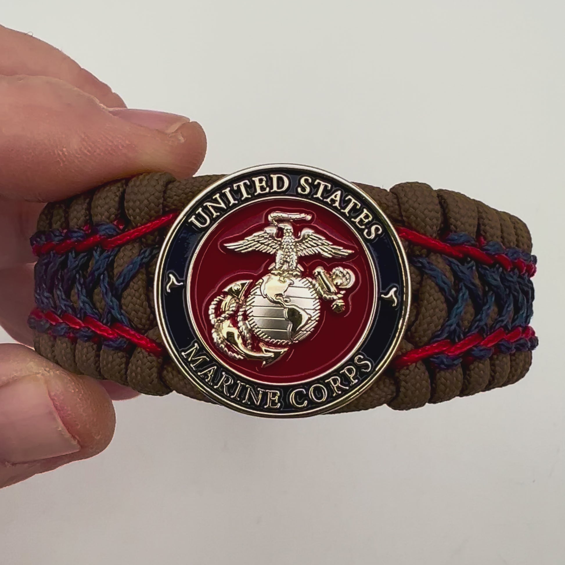 Thick and comfortable braided United States Marine Corps bracelet featuring a 24K gold and silver plated USMC officer Eagle Globe and Anchor medallion, a Cobra style tactical buckle and woven with Coyote Brown 550 paracord and Imperial Red and Navy Blue micro cord.