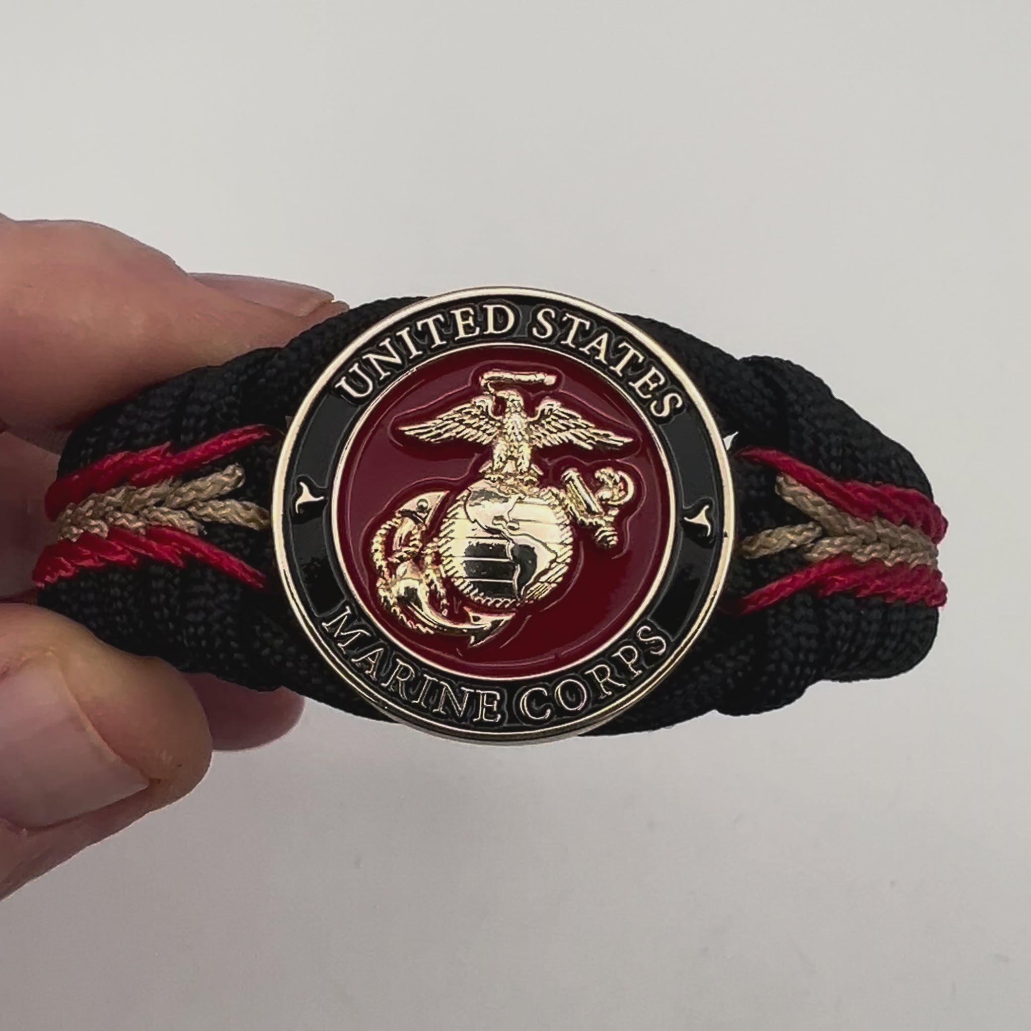 Thick, semi-rigid and comfortable braided United States Marine Corps bracelet featuring a 24K gold and silver plated USMC officer Eagle Globe and Anchor medallion, a black Cobra style tactical buckle and woven with black 550, Imperial red and gold micro paracord.