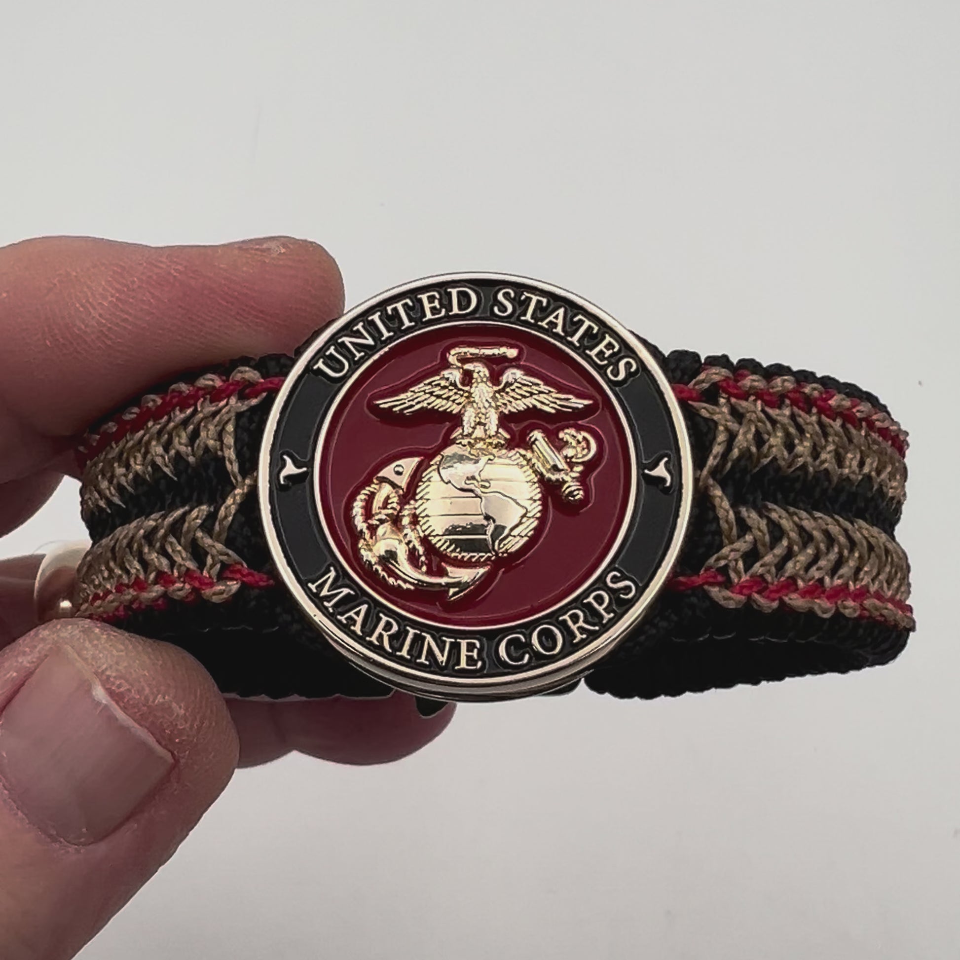Thin, narrow, flexible and comfortable braided United States Marine Corps bracelet featuring a 24K gold plated USMC Eagle Globe and Anchor medallion, a black Cobra style tactical buckle and woven with black Type-1 paracord and Imperial Red and Gold nano cord.