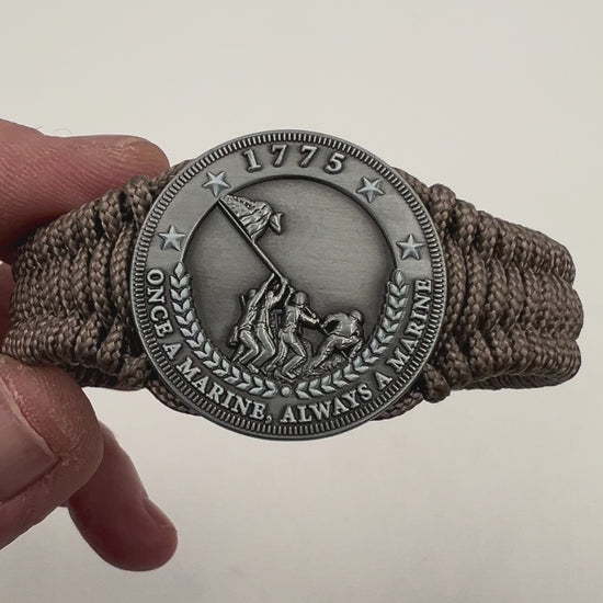 Thin, narrow, flexible and comfortable braided United States Marine Corps Iwo Jima bracelet featuring an antique silver plated Iwo Jima flag raising medallion, a silver Cobra style tactical buckle and woven with tan type-1 paracord.