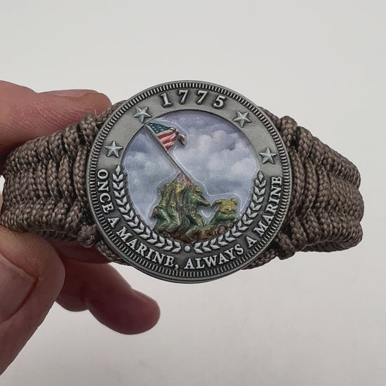 Thin, narrow, flexible and comfortable braided United States Marine Corps Iwo Jima bracelet featuring an antique silver plated UV painted Iwo Jima flag raising medallion, a silver Cobra style tactical buckle and woven with tan type-1 paracord.
