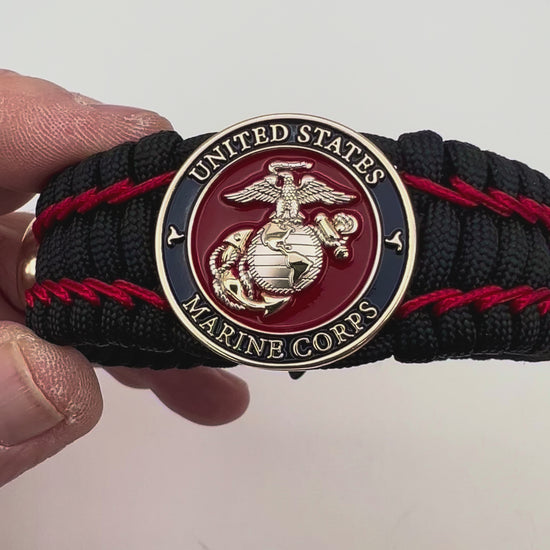 Thick and comfortable braided United States Marine Corps bracelet featuring a 24K gold and silver plated USMC officer Eagle Globe and Anchor medallion, a black Cobra style tactical buckle and woven with black 550 paracord and Imperial Red micro cord.