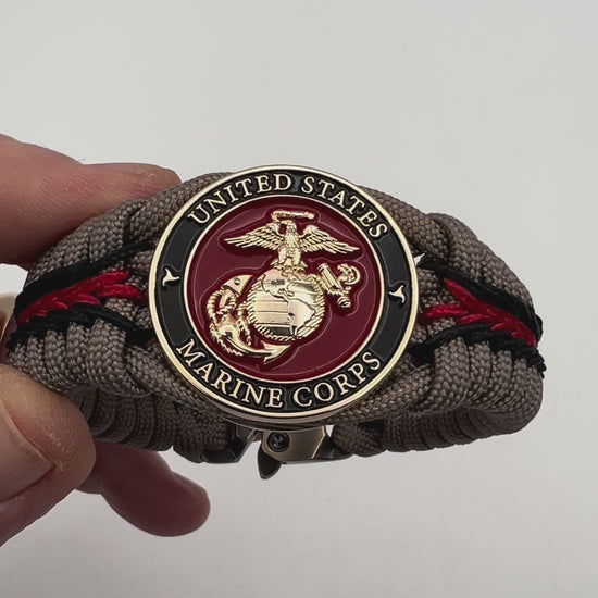 Thick, rigid and comfortable braided United States Marine Corps bracelet featuring a 24K gold plated USMC Eagle Globe and Anchor medallion, a gold Cobra style tactical buckle and woven with tan 550 paracord and Imperial Red and black micro cord.
