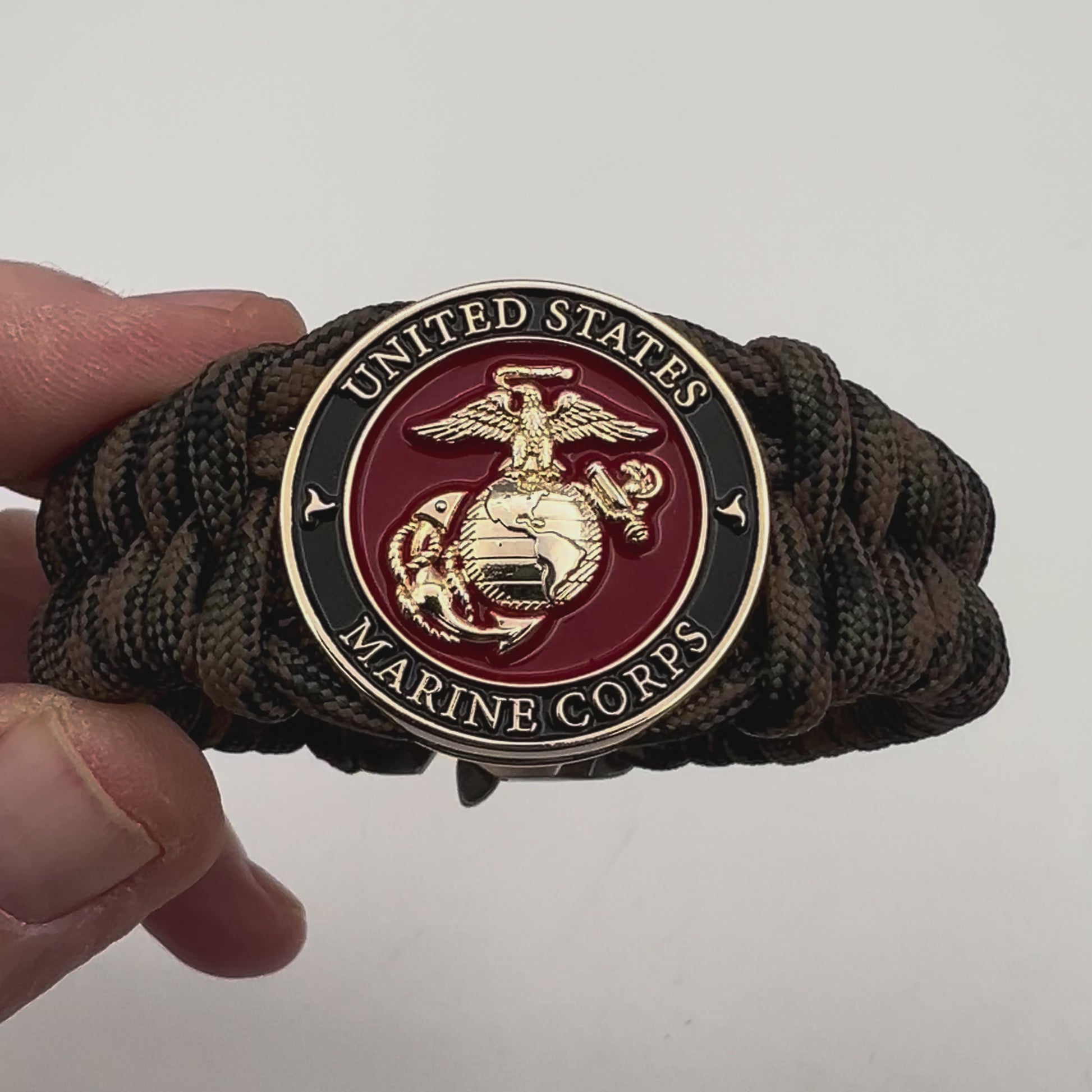 Thick, semi-rigid and comfortable braided United States Marine Corps bracelet featuring a 24K gold plated USMC Eagle Globe and Anchor medallion, a gold Cobra style tactical buckle and woven with Woodland camo 550 paracord.