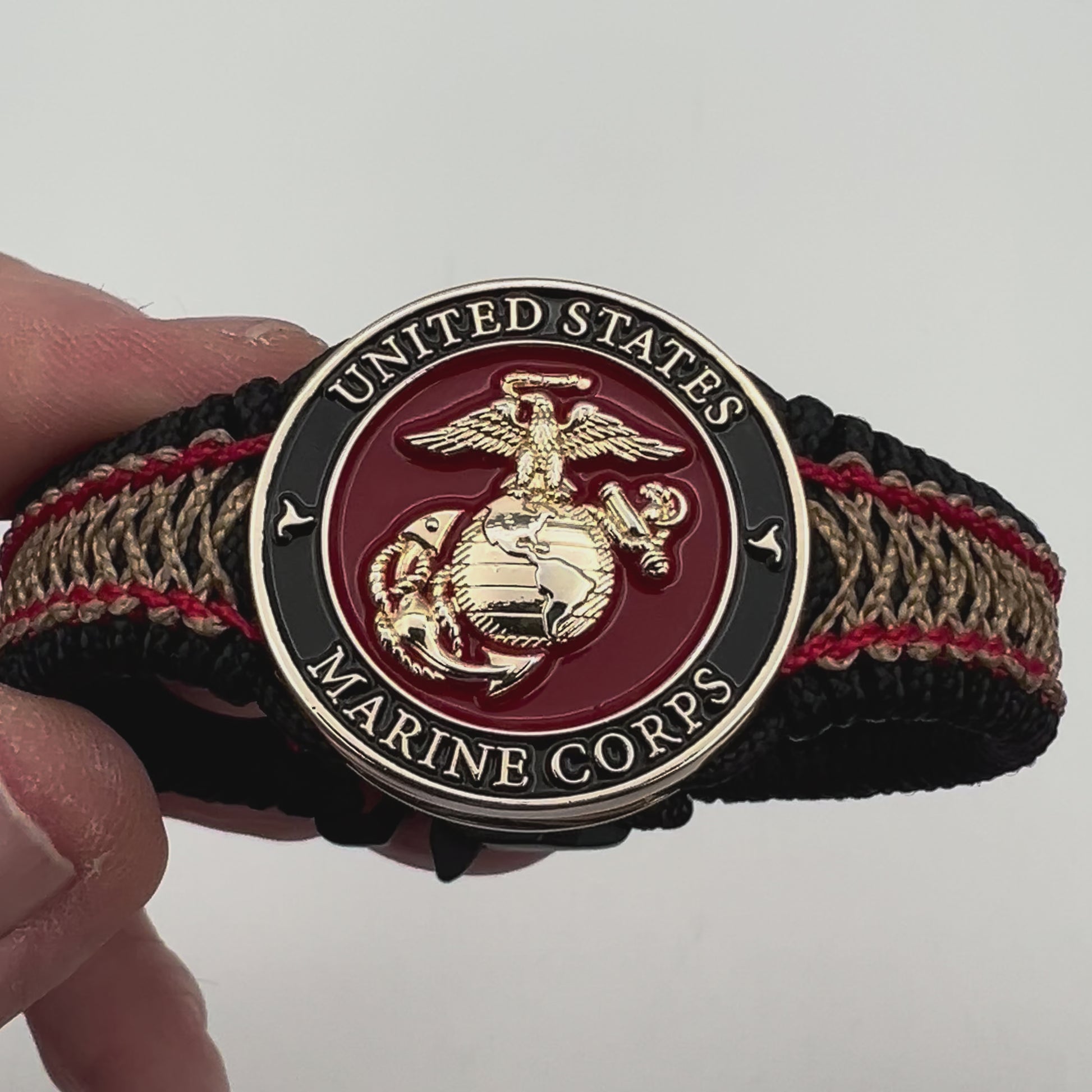 Thin, narrow, flexible and comfortable braided United States Marine Corps bracelet featuring a 24K gold plated USMC Eagle Globe and Anchor medallion, a black Cobra style tactical buckle and woven with black Type-1 paracord and Imperial Red and Gold nano cord.