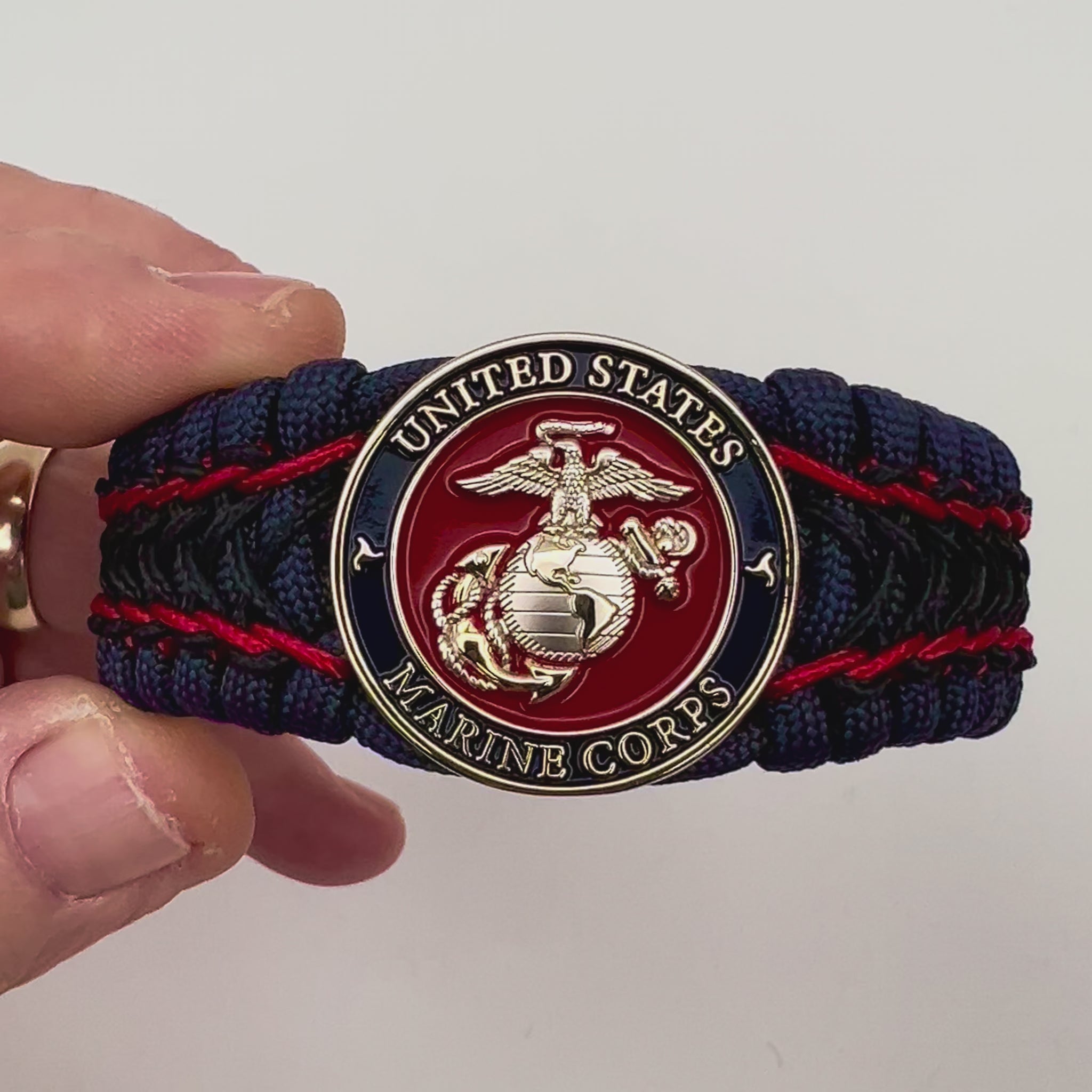 Thick and comfortable braided United States Marine Corps bracelet featuring a 24K gold and silver plated USMC officer Eagle Globe and Anchor medallion, a Cobra style tactical buckle and woven with gold 550 paracord and Imperial Red and Black micro cord.