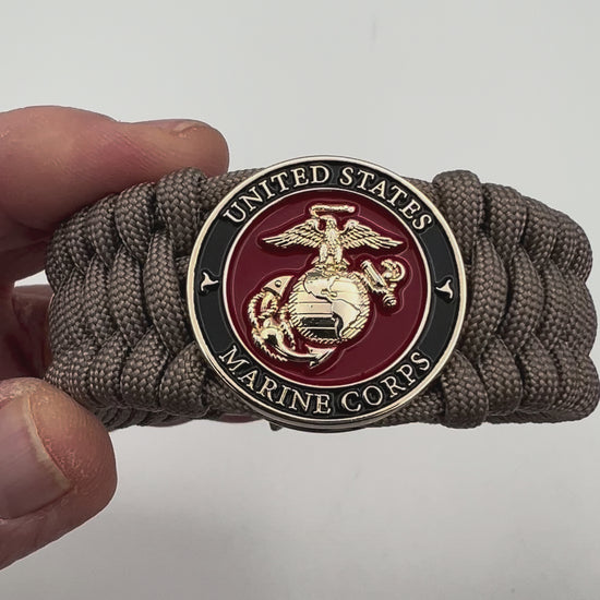 Thick, wide, semi-rigid and comfortable braided United States Marine Corps bracelet featuring a 24K gold plated USMC Eagle Globe and Anchor medallion, a gold Cobra style tactical buckle and woven with tan 550 paracord.