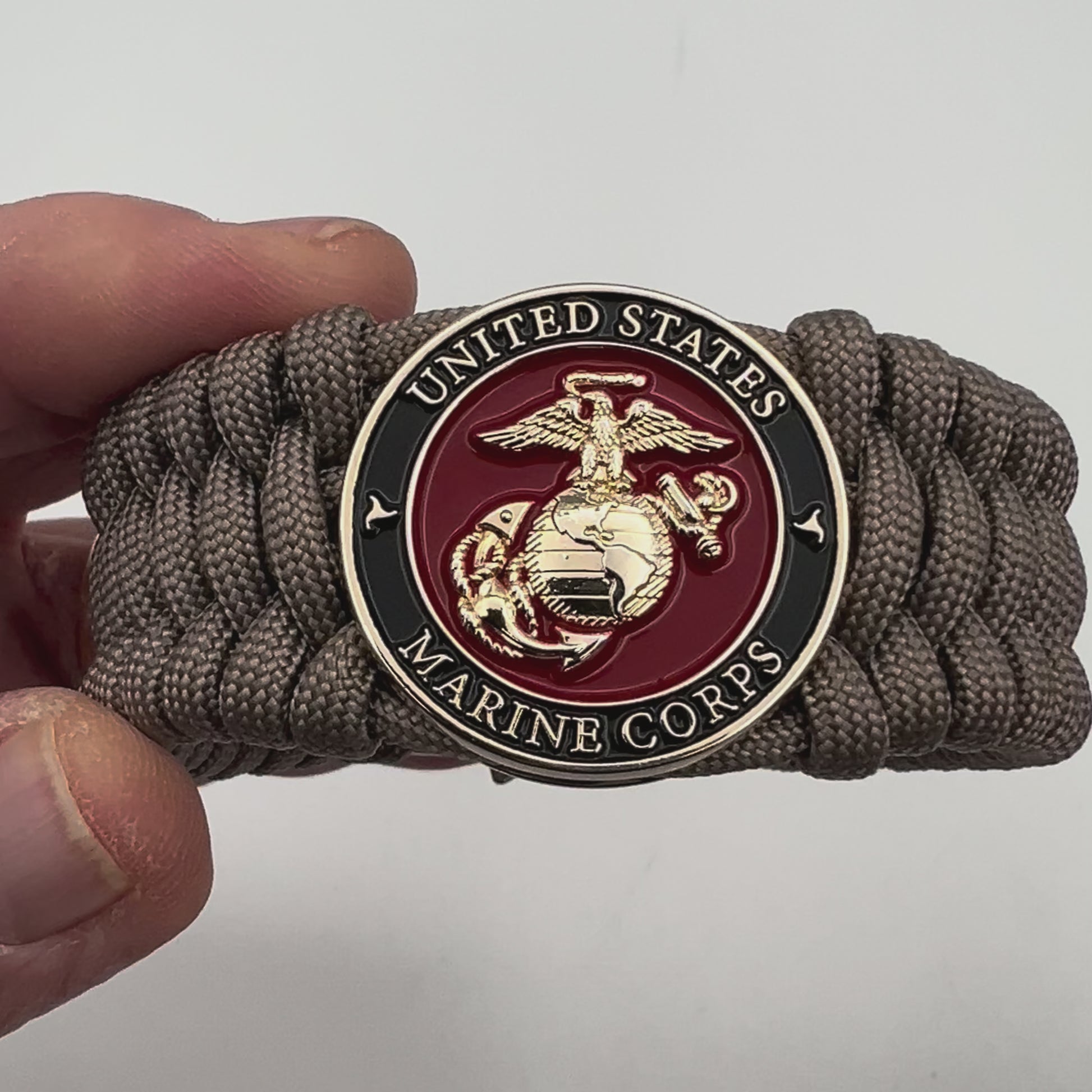 Thick, wide, semi-rigid and comfortable braided United States Marine Corps bracelet featuring a 24K gold plated USMC Eagle Globe and Anchor medallion, a gold Cobra style tactical buckle and woven with tan 550 paracord.