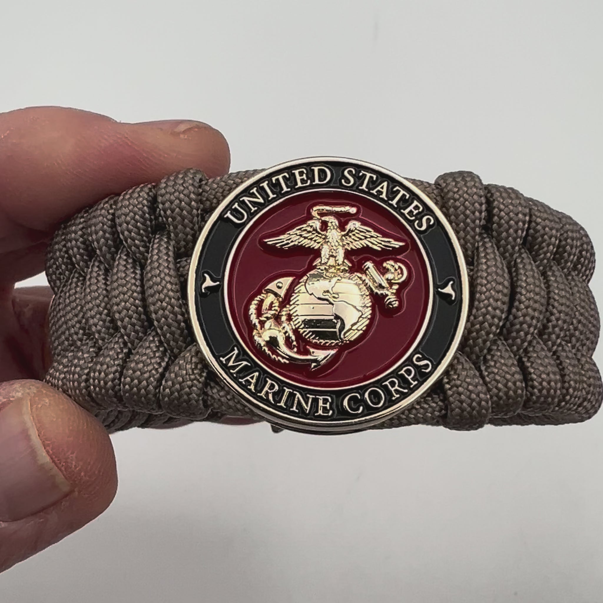 Thick, wide, semi-rigid and comfortable braided United States Marine Corps bracelet featuring a 24K gold plated USMC Eagle Globe and Anchor medallion, a gold Cobra style tactical buckle and woven with tan 550 paracord.