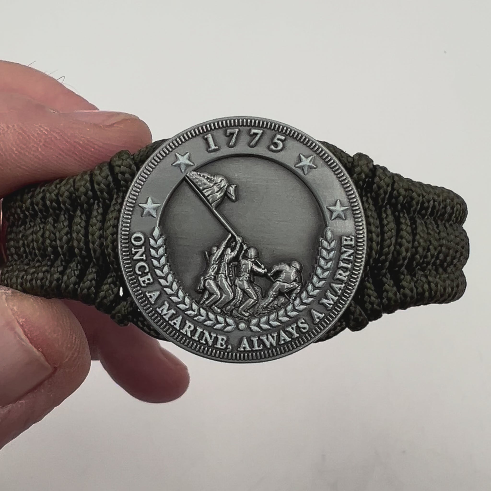 Thin, narrow, flexible and comfortable braided United States Marine Corps Iwo Jima bracelet featuring an antique silver plated UV painted Iwo Jima flag raising medallion, a silver Cobra style tactical buckle and woven with Olive Drab type-1 paracord.