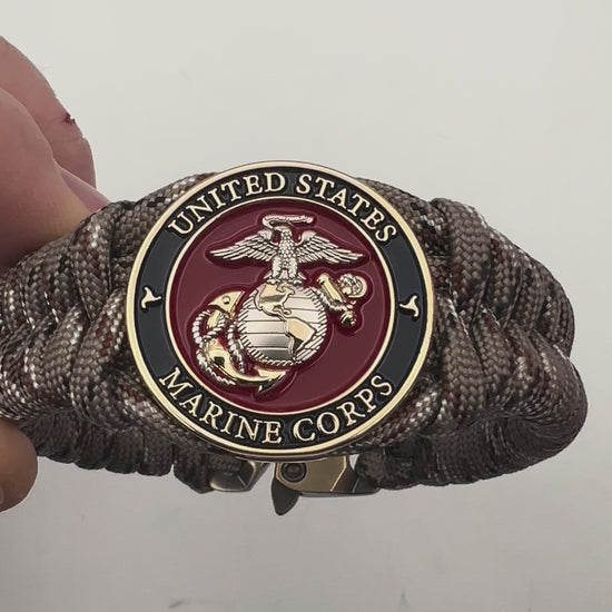 Thick and comfortable braided United States Marine Corps bracelet featuring a 24K gold and silver plated USMC officer Eagle Globe and Anchor medallion, a Cobra style tactical buckle and woven with Desert Camo paracord.