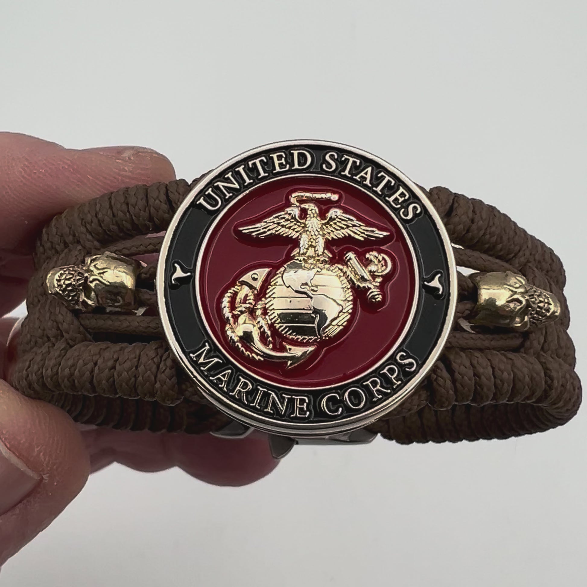 Thin, medium width, flexible and comfortable braided United States Marine Corps bracelet featuring a 24K gold plated USMC officer Eagle Globe and Anchor medallion, two gold plated skulls, a gold Cobra style tactical buckle and woven with Coyote Brown Type-1 paracord.