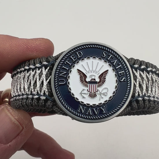 Thin, wide and comfortable braided United States Navy bracelet featuring an antique silver plated Navy medallion, a silver Cobra style tactical buckle and woven with Charcoal Gray Type-1 paracord and Nay Blue and White nano cord.