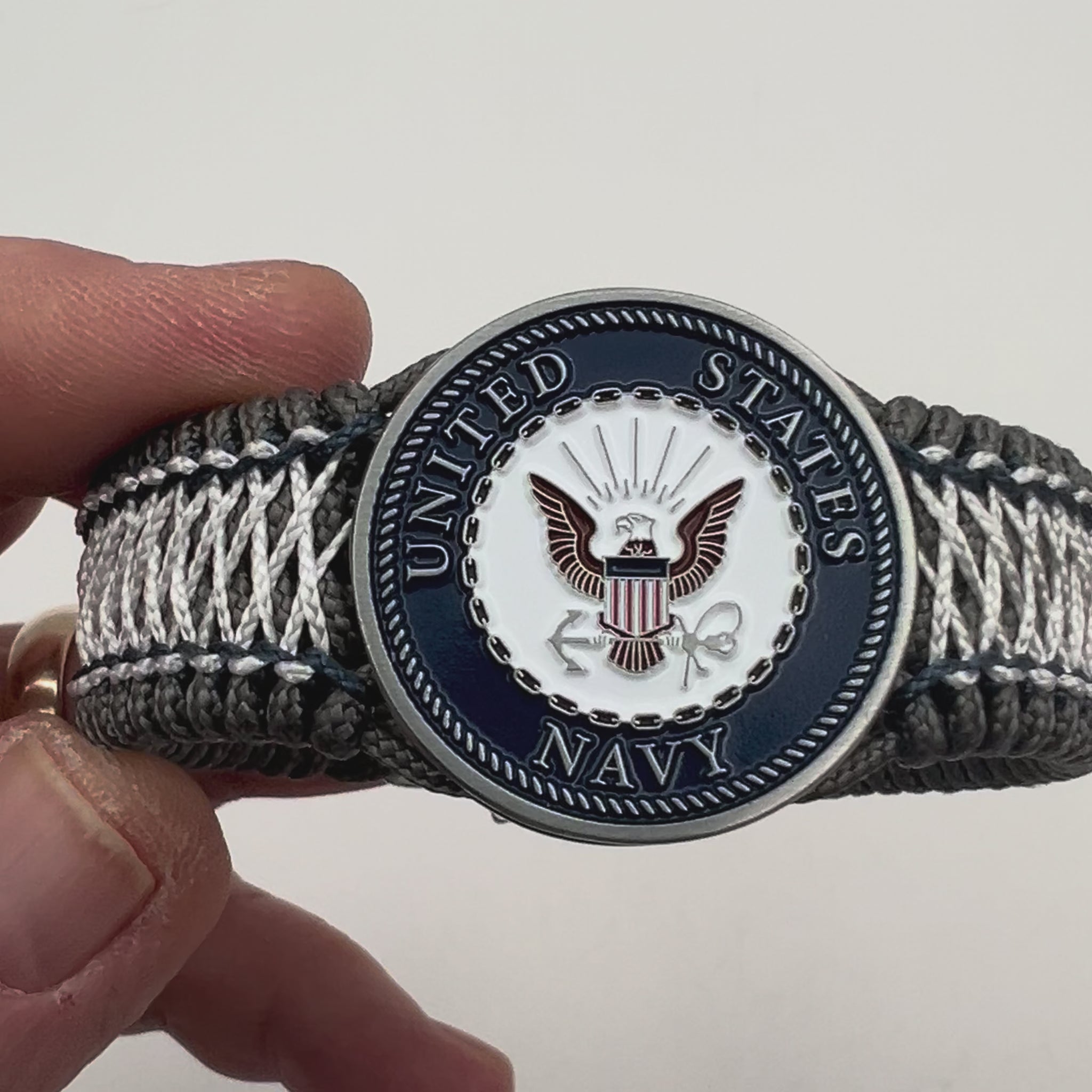 Thin, wide and comfortable braided United States Navy bracelet featuring an antique silver plated Navy medallion, a silver Cobra style tactical buckle and woven with Charcoal Gray Type-1 paracord and Nay Blue and White nano cord.