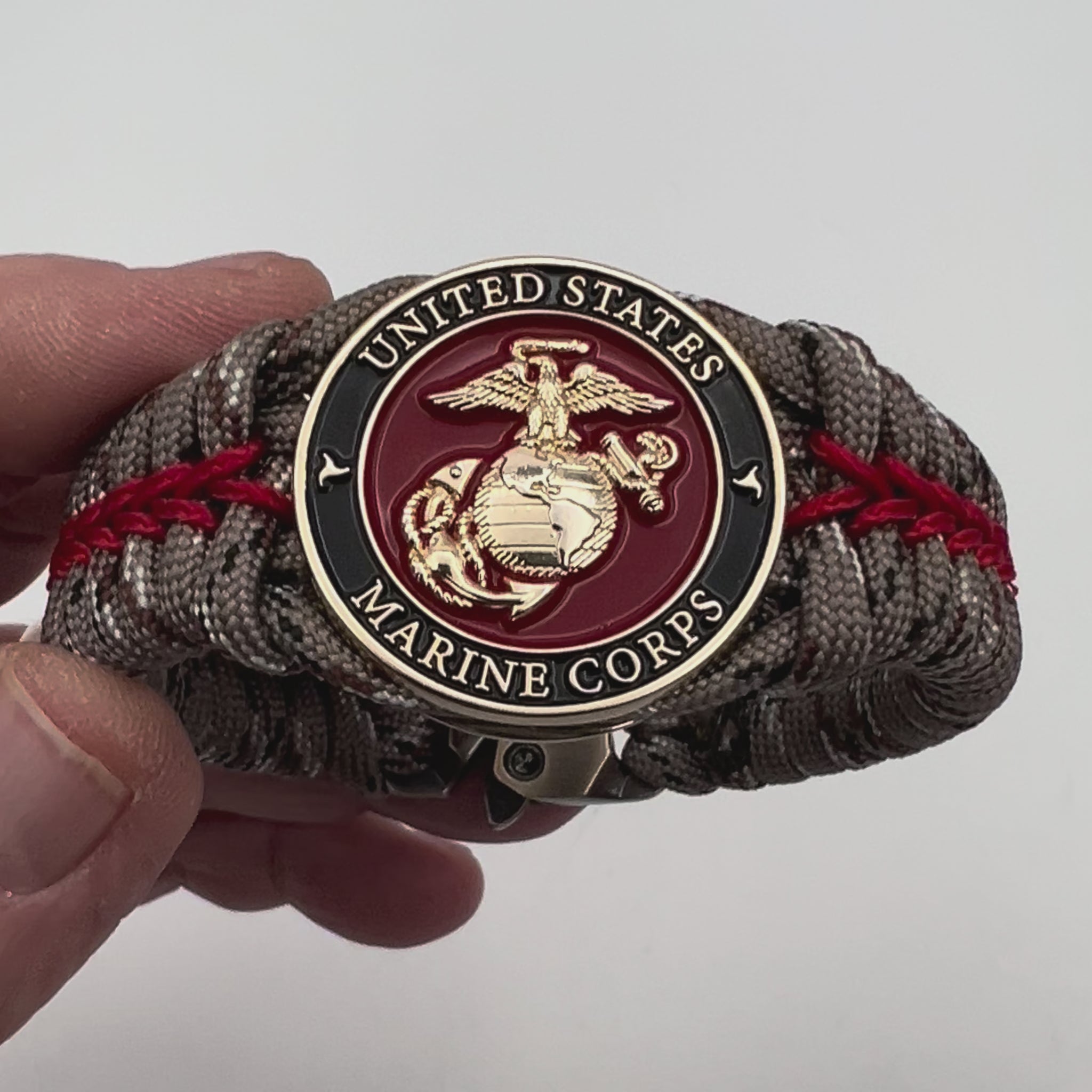 Thick, rigid and comfortable braided United States Marine Corps bracelet featuring a 24K gold plated USMC Eagle Globe and Anchor medallion, a gold Cobra style tactical buckle and woven with Desert Camo 550 paracord and Imperial Red micro cord.