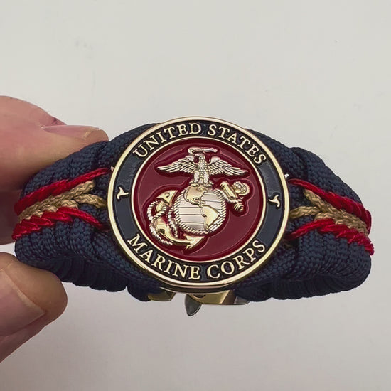 Thick and comfortable braided United States Marine Corps bracelet featuring a 24K gold and silver plated USMC officer Eagle Globe and Anchor medallion, a Cobra style tactical buckle and woven with Navy blue, Imperial red and gold paracord.