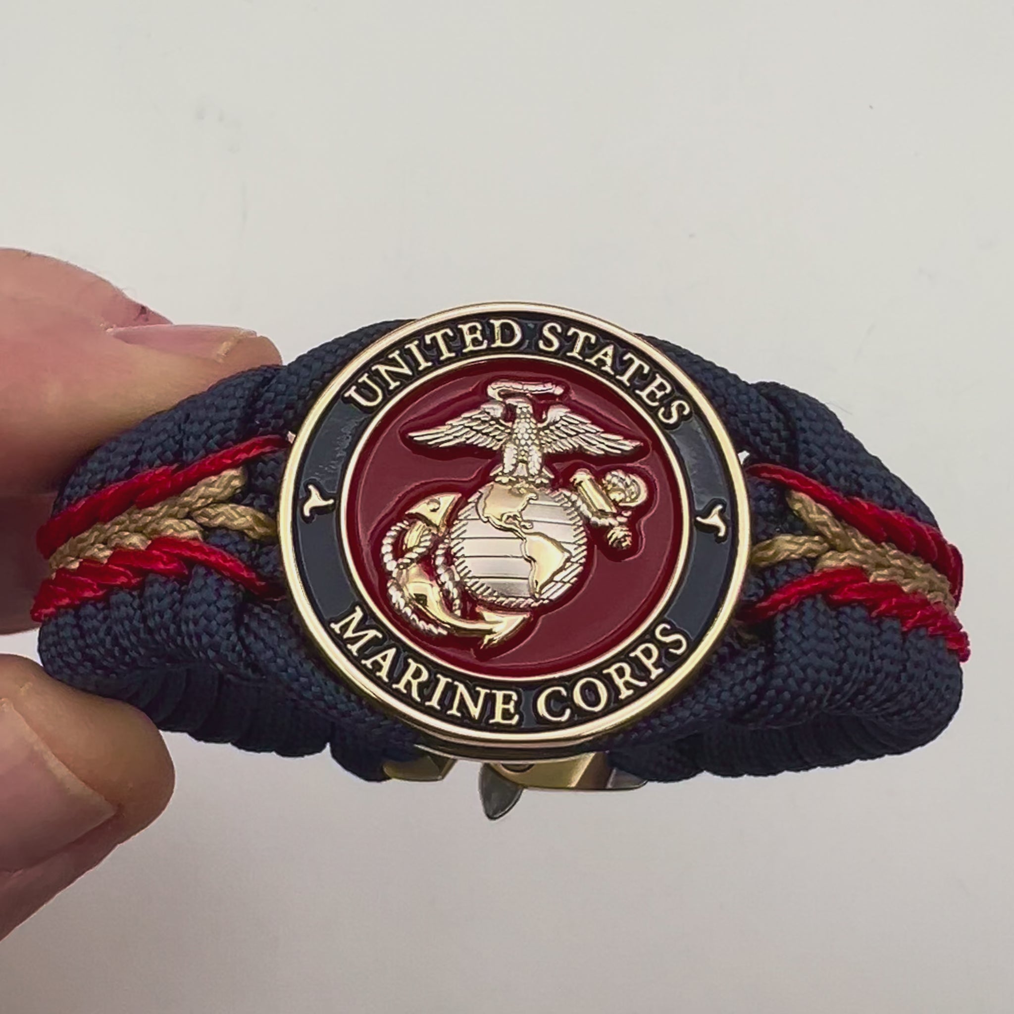 Thick and comfortable braided United States Marine Corps bracelet featuring a 24K gold and silver plated USMC officer Eagle Globe and Anchor medallion, a Cobra style tactical buckle and woven with Navy blue, Imperial red and gold paracord.