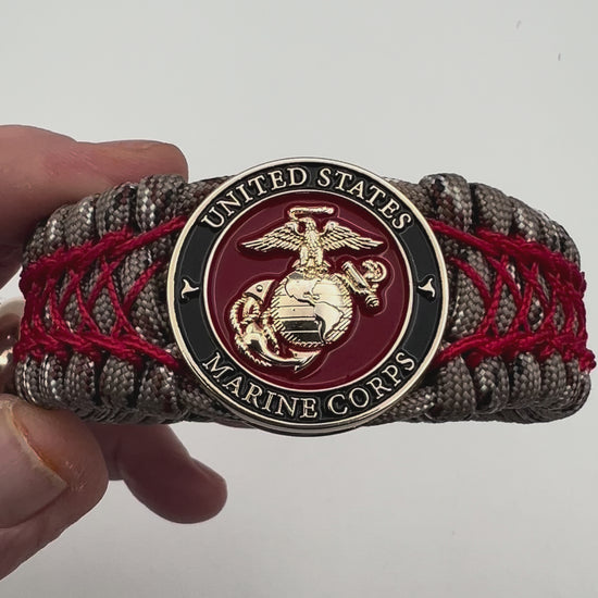 Thick, wide, rigid and comfortable braided United States Marine Corps bracelet featuring a 24K gold plated USMC Eagle Globe and Anchor medallion, a gold Cobra style tactical buckle and woven with Desert Camo 550 paracord and Imperial Red nano and micro cord.