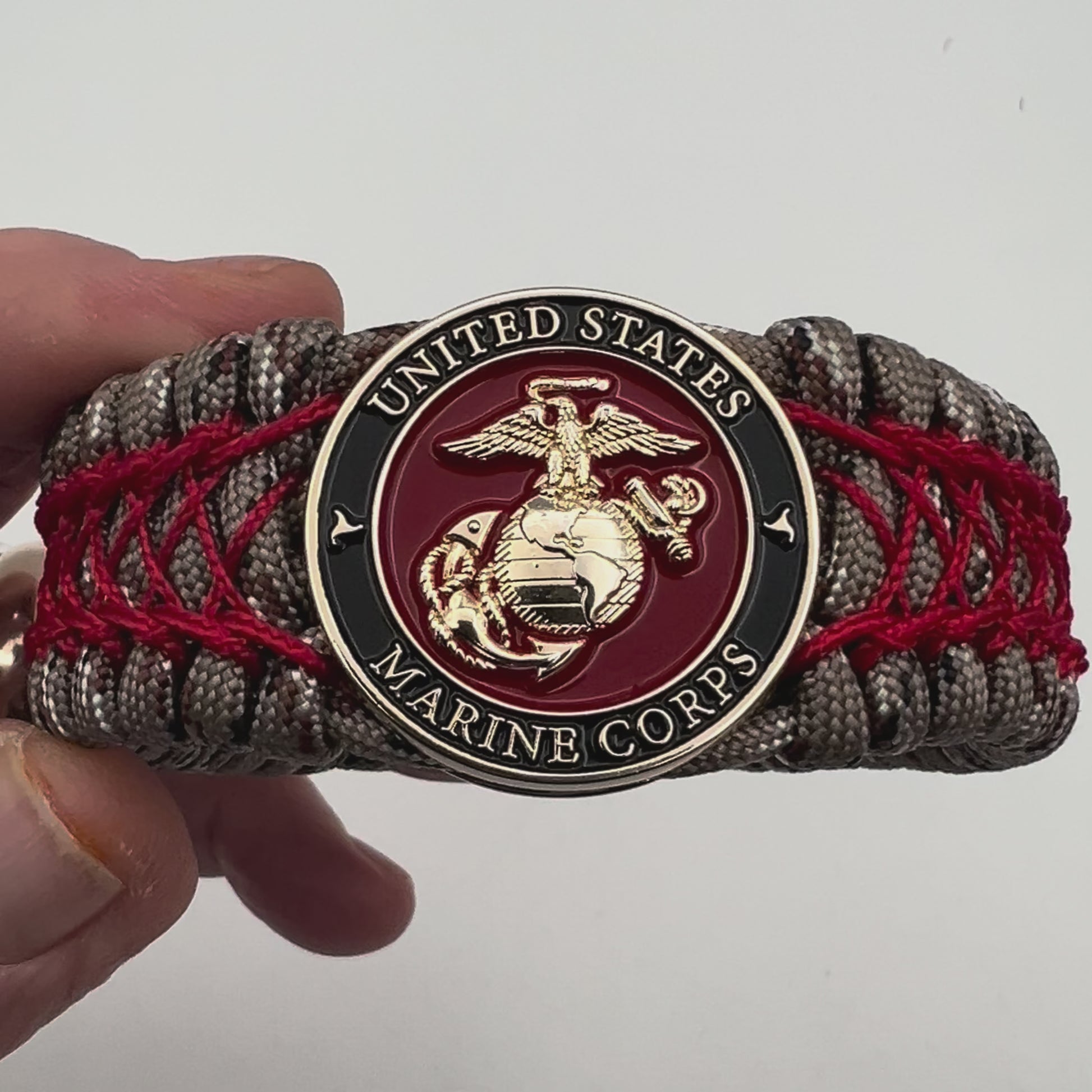 Thick, wide, rigid and comfortable braided United States Marine Corps bracelet featuring a 24K gold plated USMC Eagle Globe and Anchor medallion, a gold Cobra style tactical buckle and woven with Desert Camo 550 paracord and Imperial Red nano and micro cord.