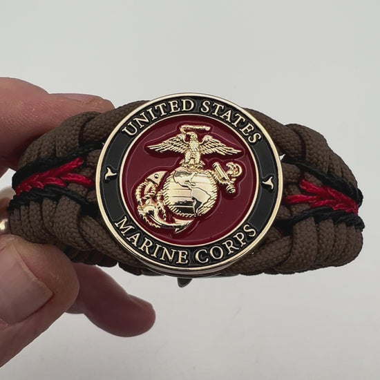 Thick, rigid and comfortable braided United States Marine Corps bracelet featuring a 24K gold plated USMC Eagle Globe and Anchor medallion, a gold Cobra style tactical buckle and woven with Coyote Brown 550 paracord and Imperial Red and black micro cord.