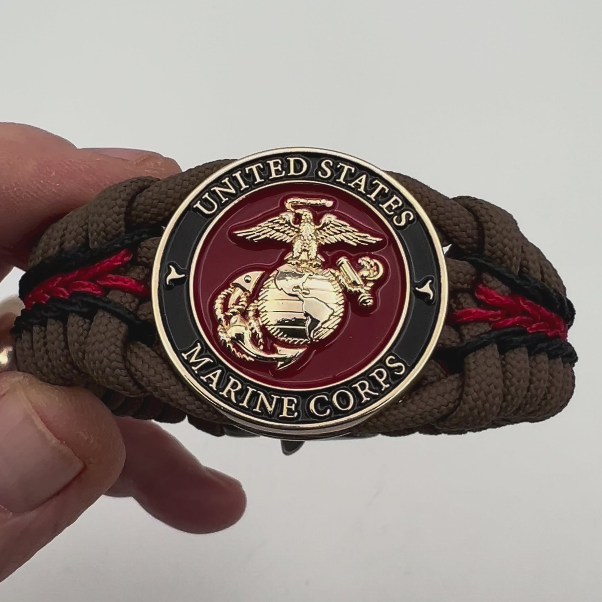 Thick, rigid and comfortable braided United States Marine Corps bracelet featuring a 24K gold plated USMC Eagle Globe and Anchor medallion, a gold Cobra style tactical buckle and woven with Coyote Brown 550 paracord and Imperial Red and black micro cord.