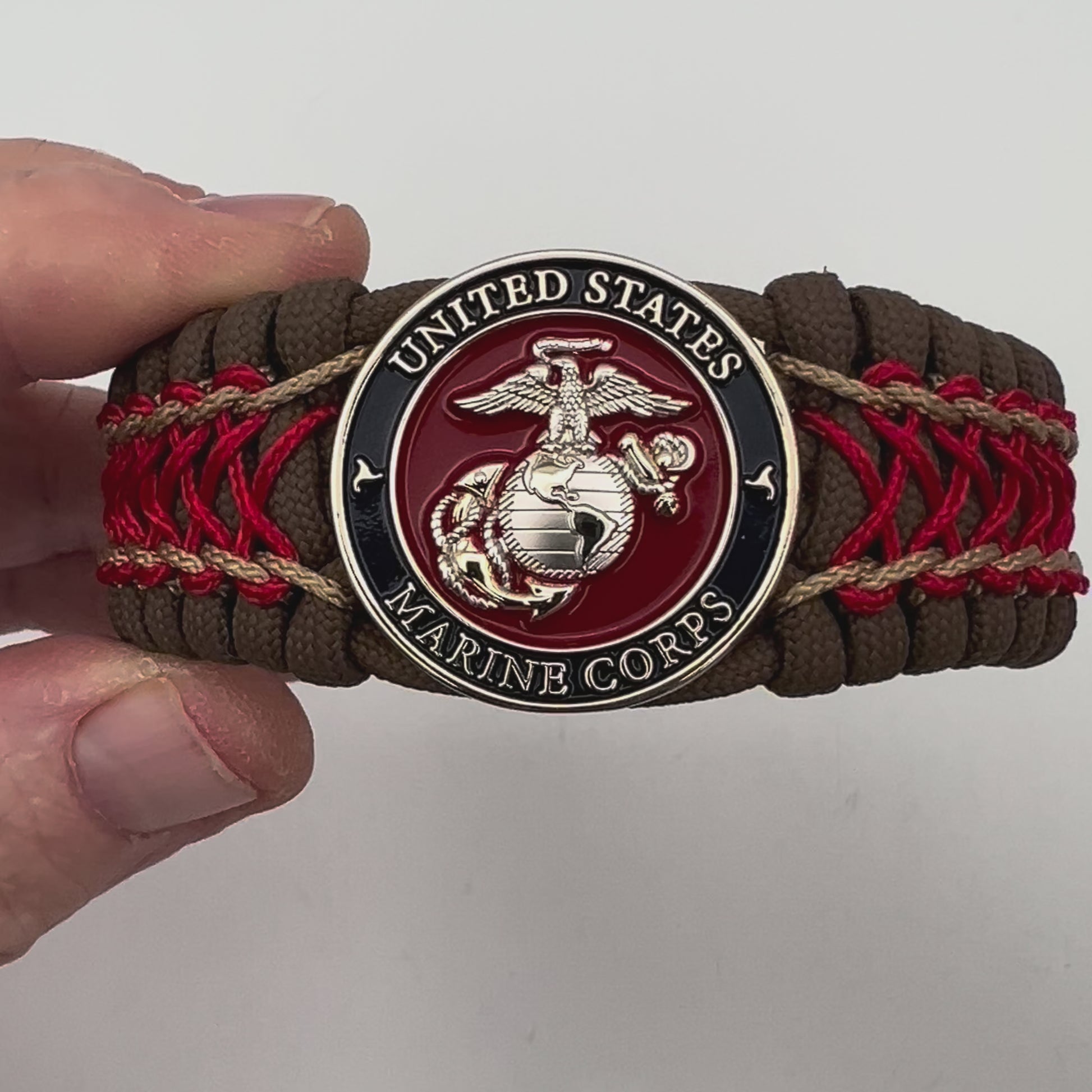 Thick and comfortable braided United States Marine Corps bracelet featuring a 24K gold and silver plated USMC officer Eagle Globe and Anchor medallion, a Cobra style tactical buckle and woven with Coyote Brown 550 paracord and Imperial Red and gold micro cord.