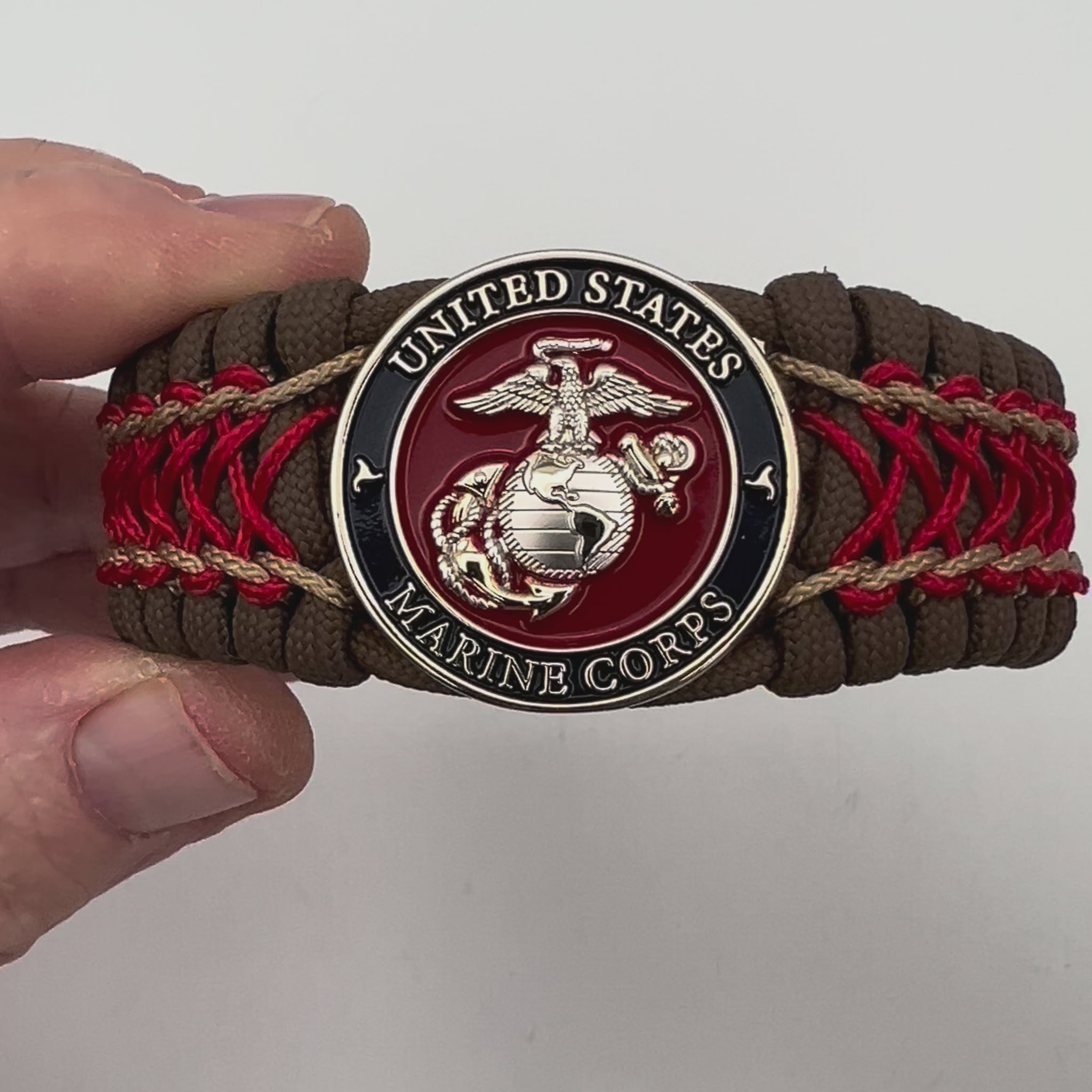 Thick and comfortable braided United States Marine Corps bracelet featuring a 24K gold and silver plated USMC officer Eagle Globe and Anchor medallion, a Cobra style tactical buckle and woven with Coyote Brown 550 paracord and Imperial Red and gold micro cord.