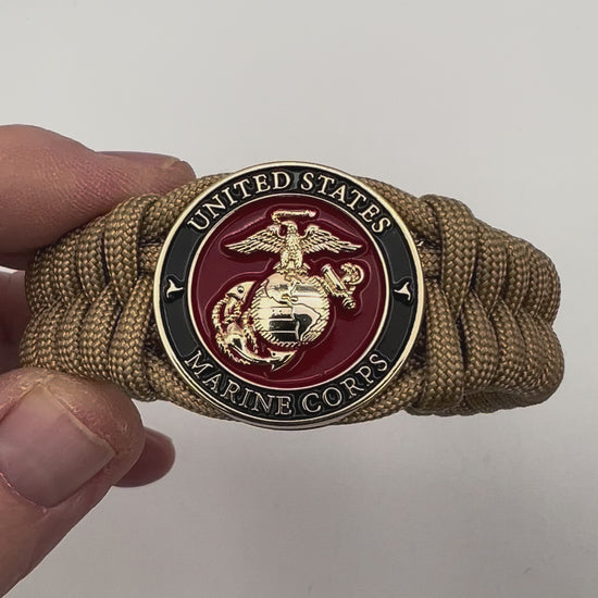 Thick, semi-rigid and comfortable braided United States Marine Corps bracelet featuring a 24K gold plated USMC officer Eagle Globe and Anchor medallion, a gold Cobra style tactical buckle and woven with gold 550 paracord.