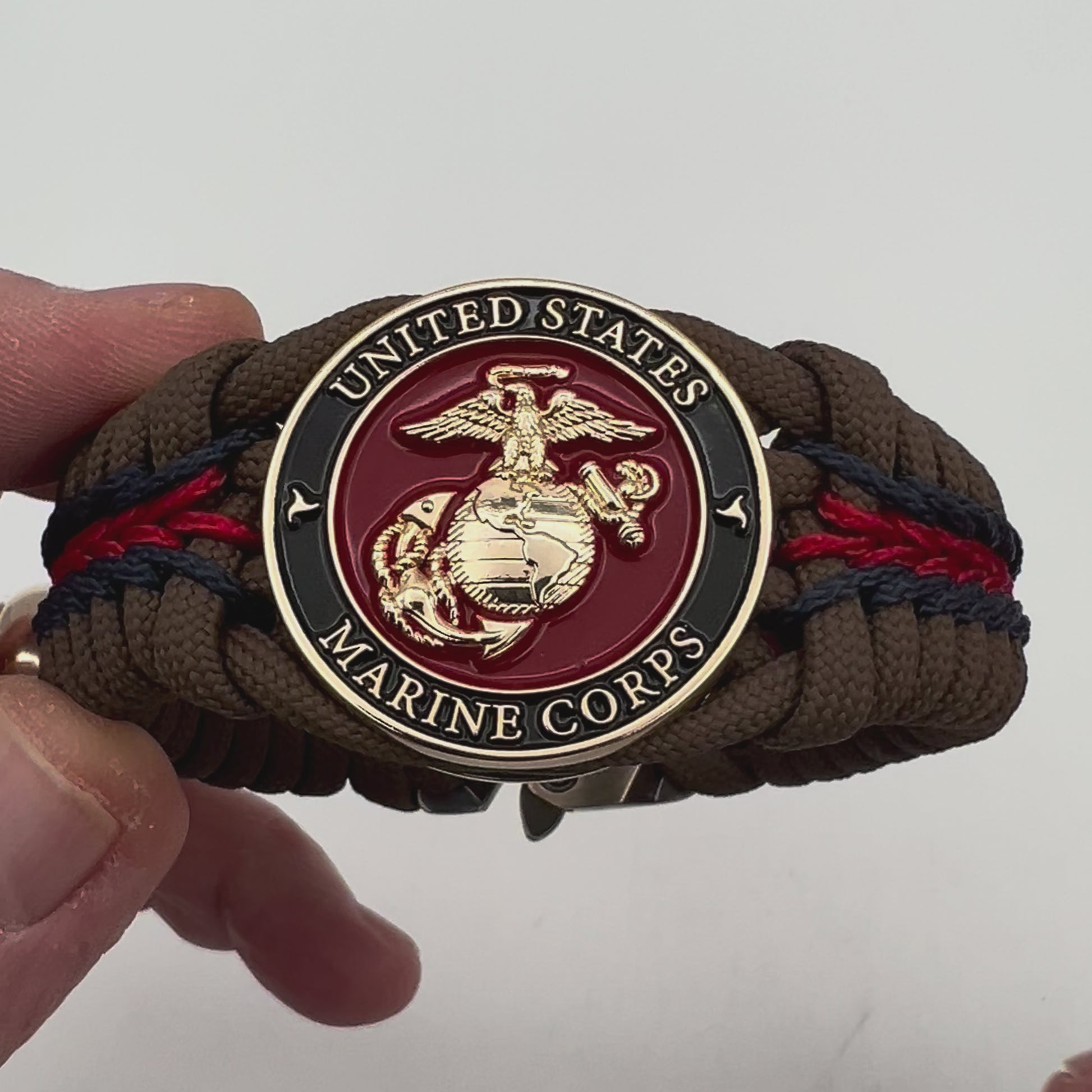 Thick, rigid and comfortable braided United States Marine Corps bracelet featuring a 24K gold plated USMC Eagle Globe and Anchor medallion, a gold Cobra style tactical buckle and woven with Coyote Brown 550 paracord and Imperial Red and Navy Blue micro cord.