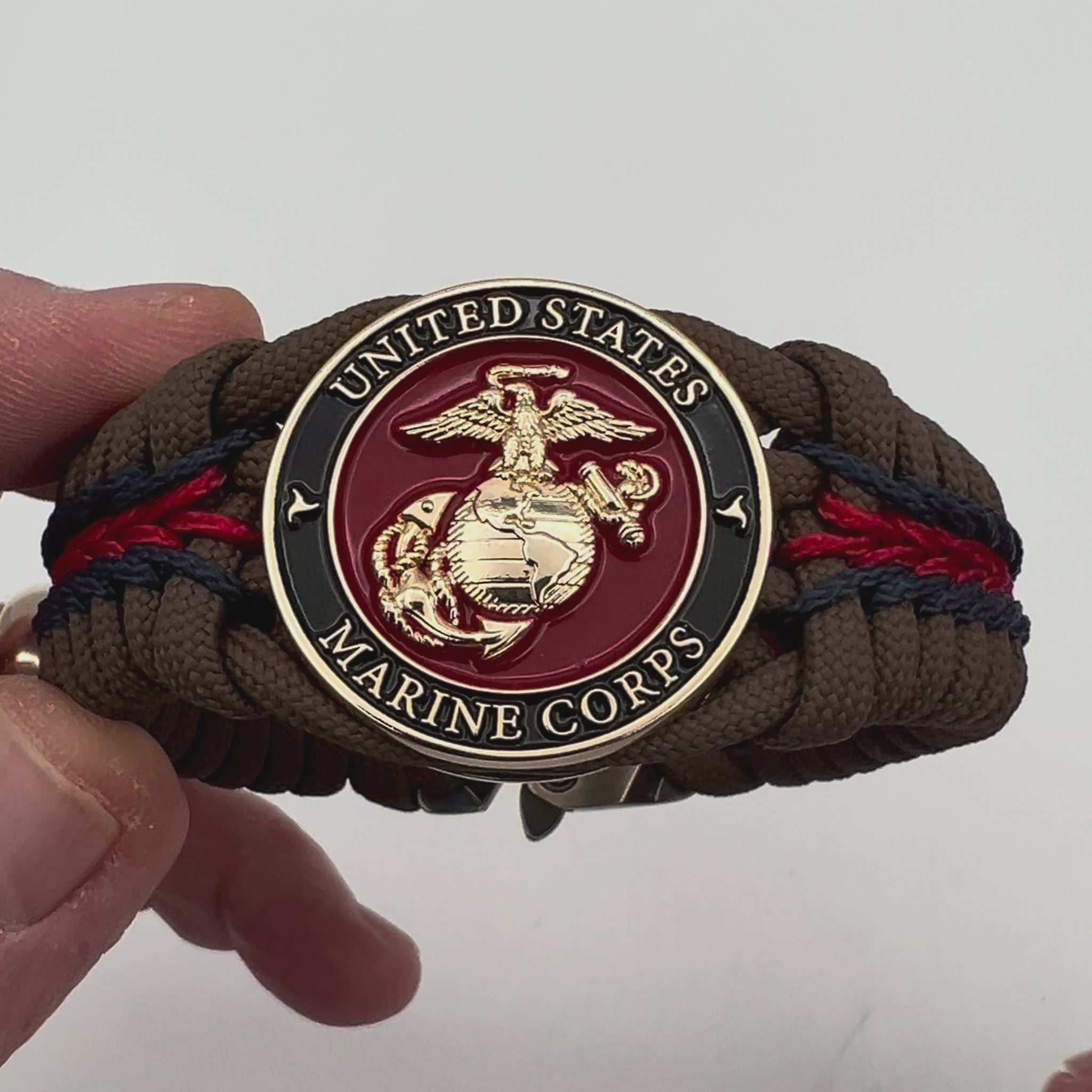 Thick, rigid and comfortable braided United States Marine Corps bracelet featuring a 24K gold plated USMC Eagle Globe and Anchor medallion, a gold Cobra style tactical buckle and woven with Coyote Brown 550 paracord and Imperial Red and Navy Blue micro cord.